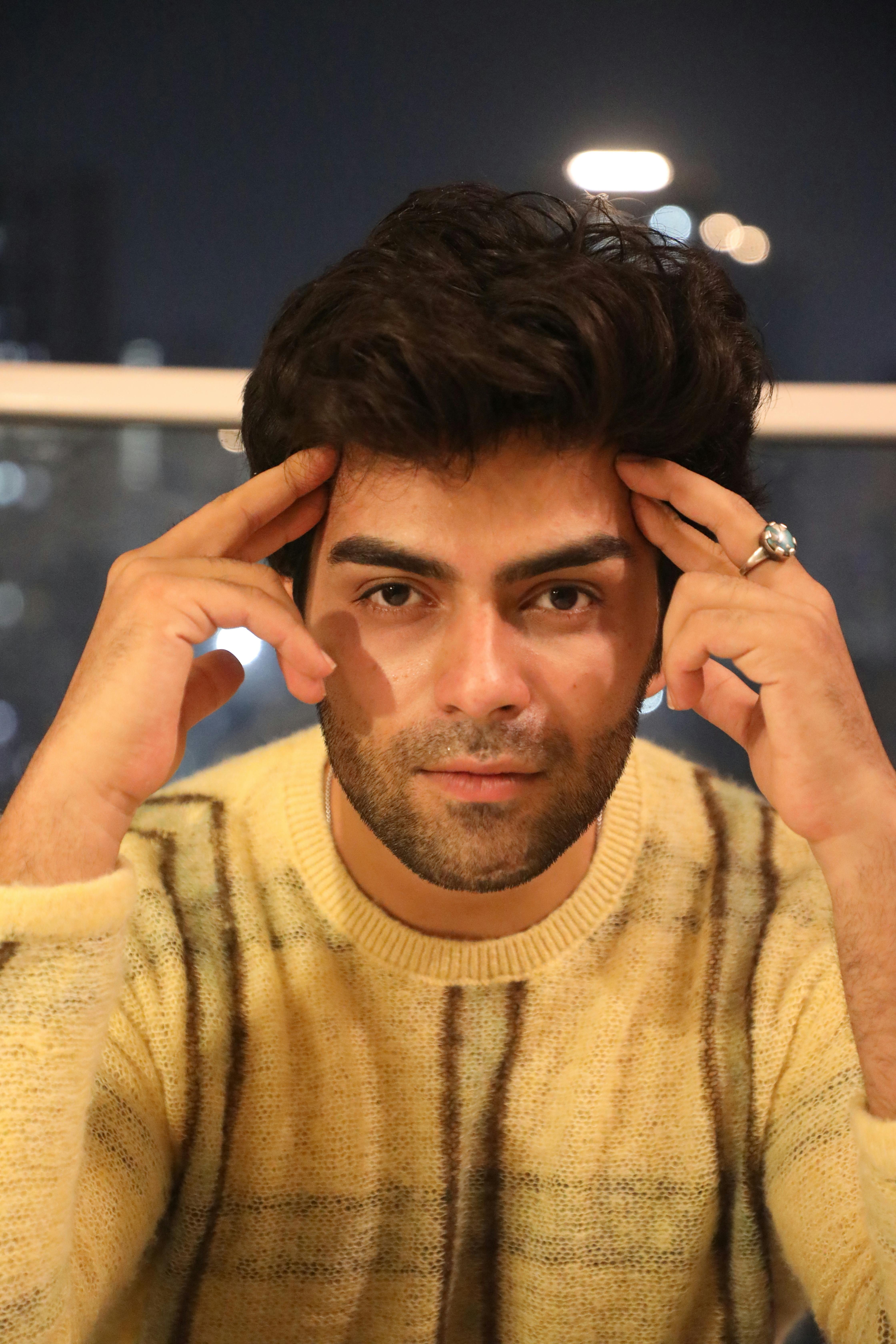 Portrait of a young man in a cozy sweater, looking thoughtful at night indoors.