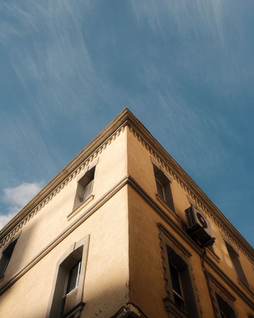 Free View of a building corner with warm light and clear blue skies, emphasizing modern urban architecture. Stock Photo