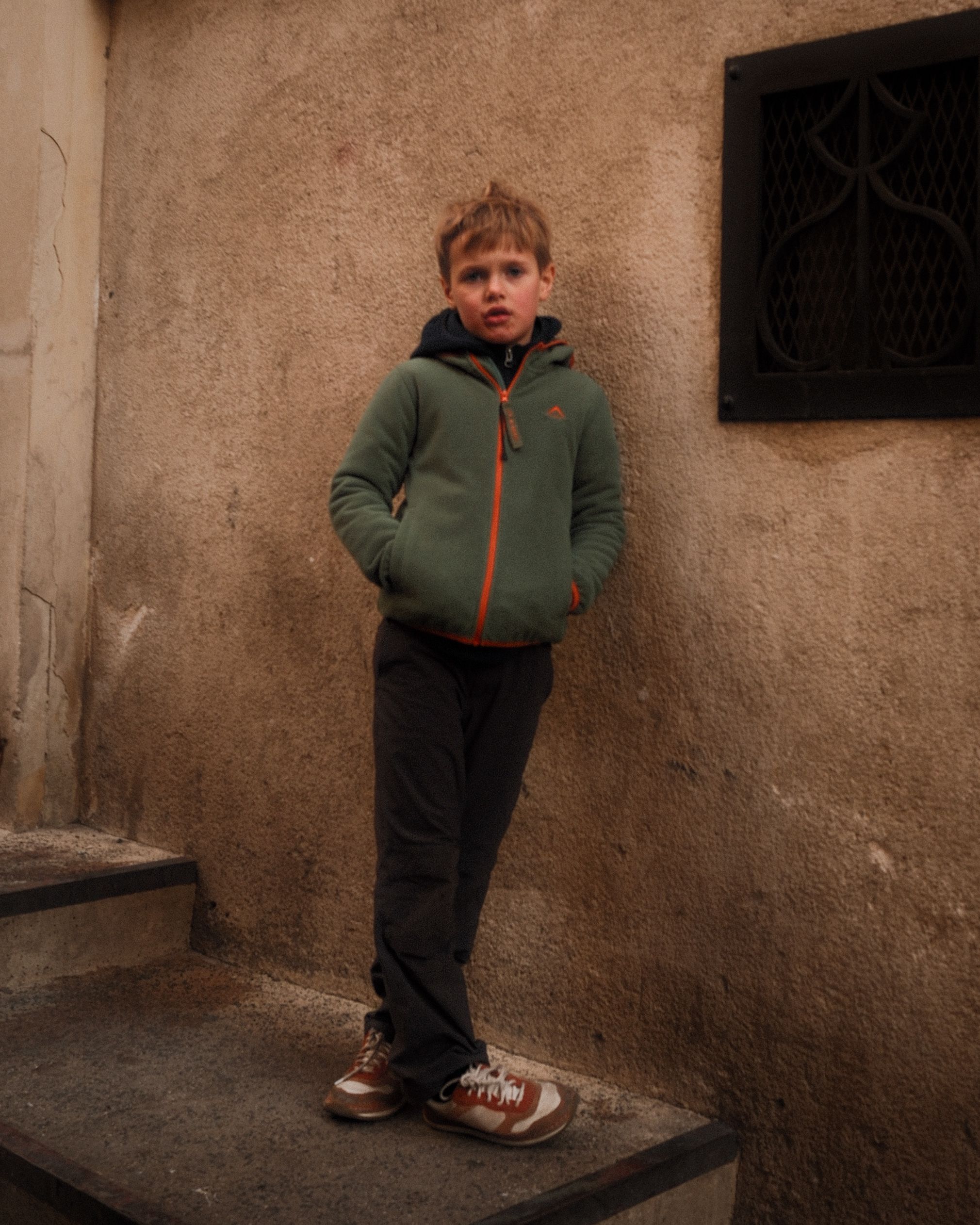 Young Boy Standing Against a Rustic Wall · Free Stock Photo