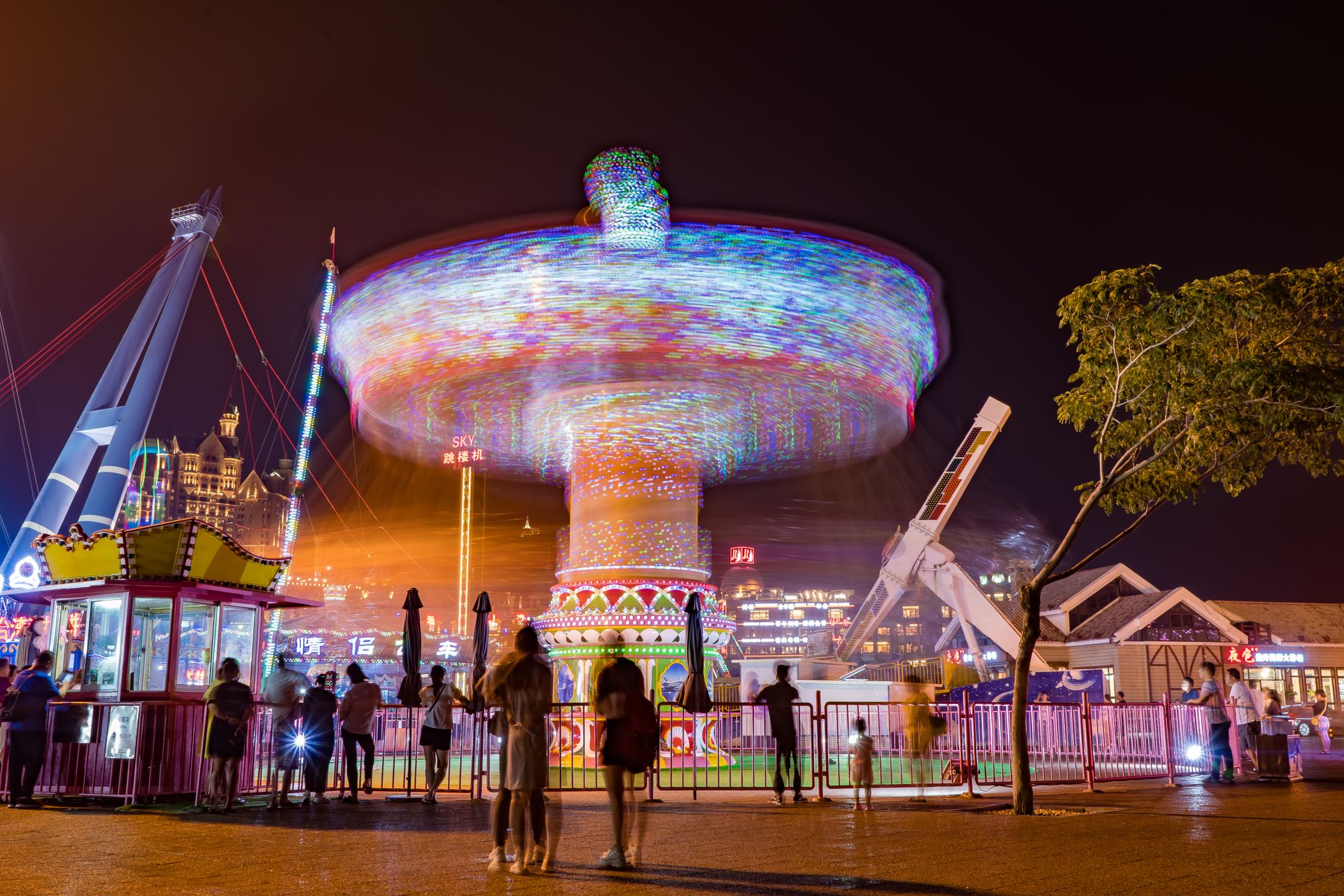 Long-exposure photo of a colorful carousel in Dalian, China, capturing motion blur at night.