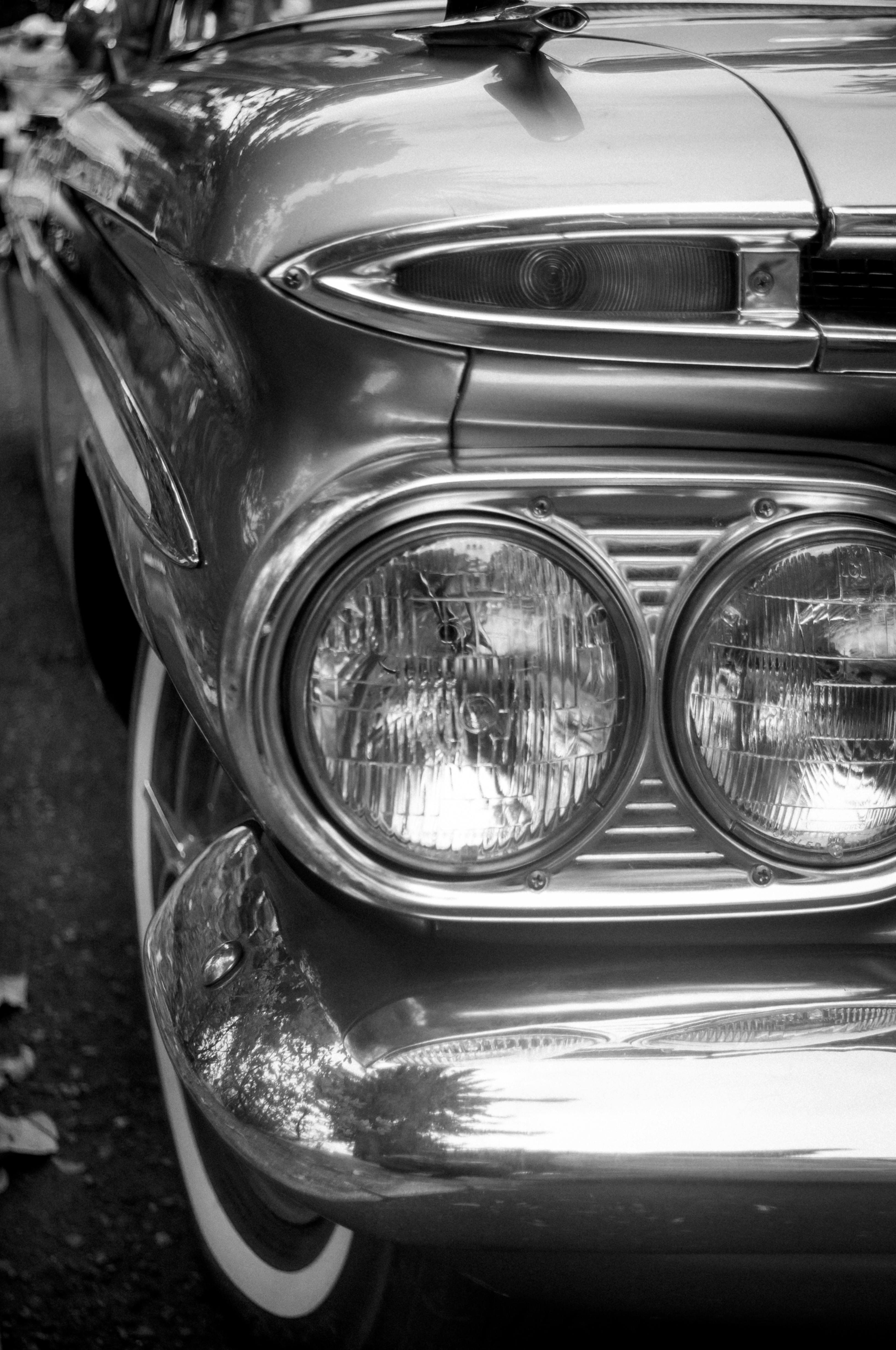 Ücretsiz Klasik bir otomobilin siyah beyaz fotoğrafı, zarif vintage farlarını ve krom detaylarını sergiliyor. Stok Fotoğraflar