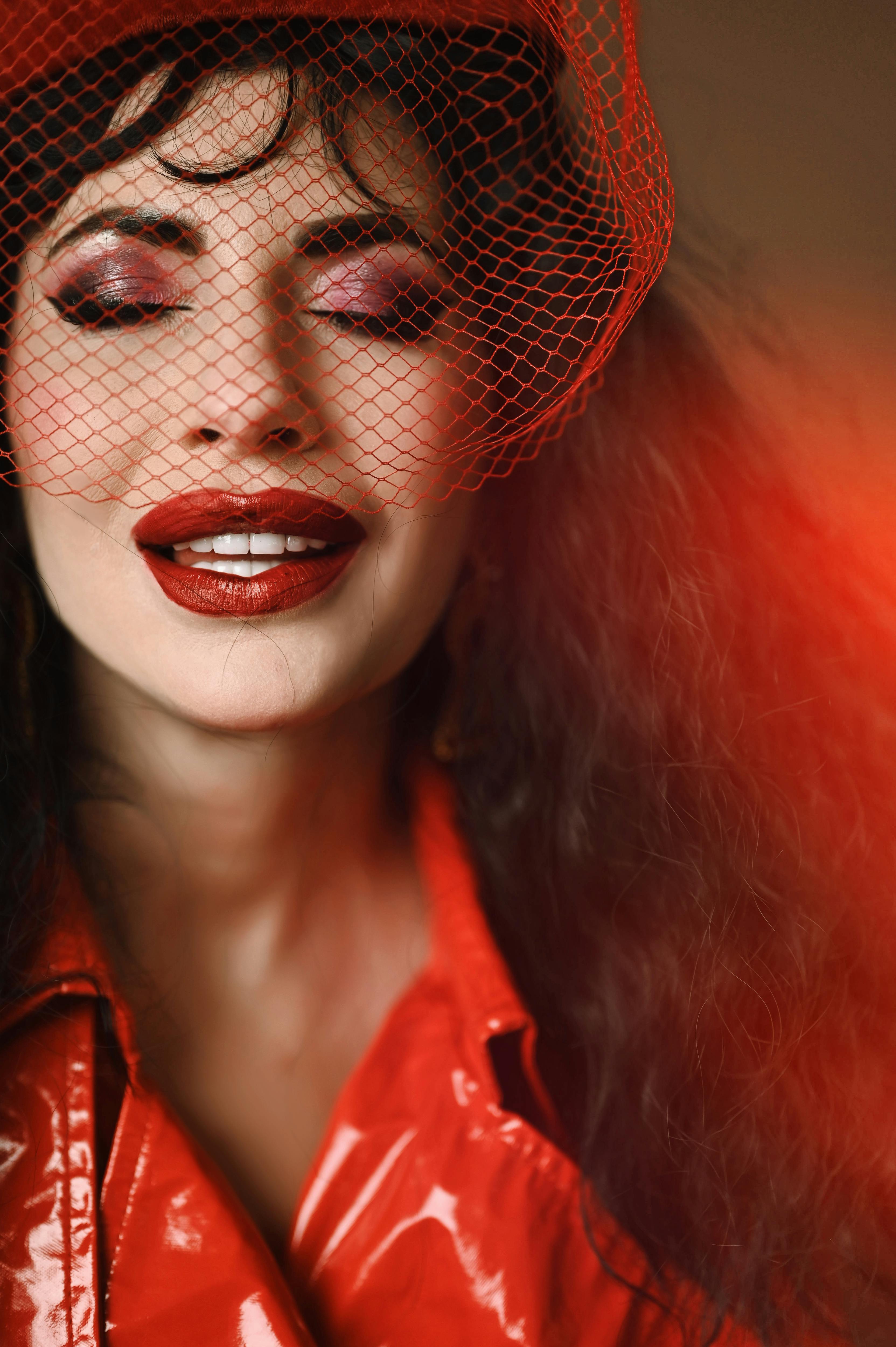 Ücretsiz Kırmızı bir kıyafet ve tül peçeyle kapalı bir mekanda poz veren zarif bir kadın. Stok Fotoğraflar