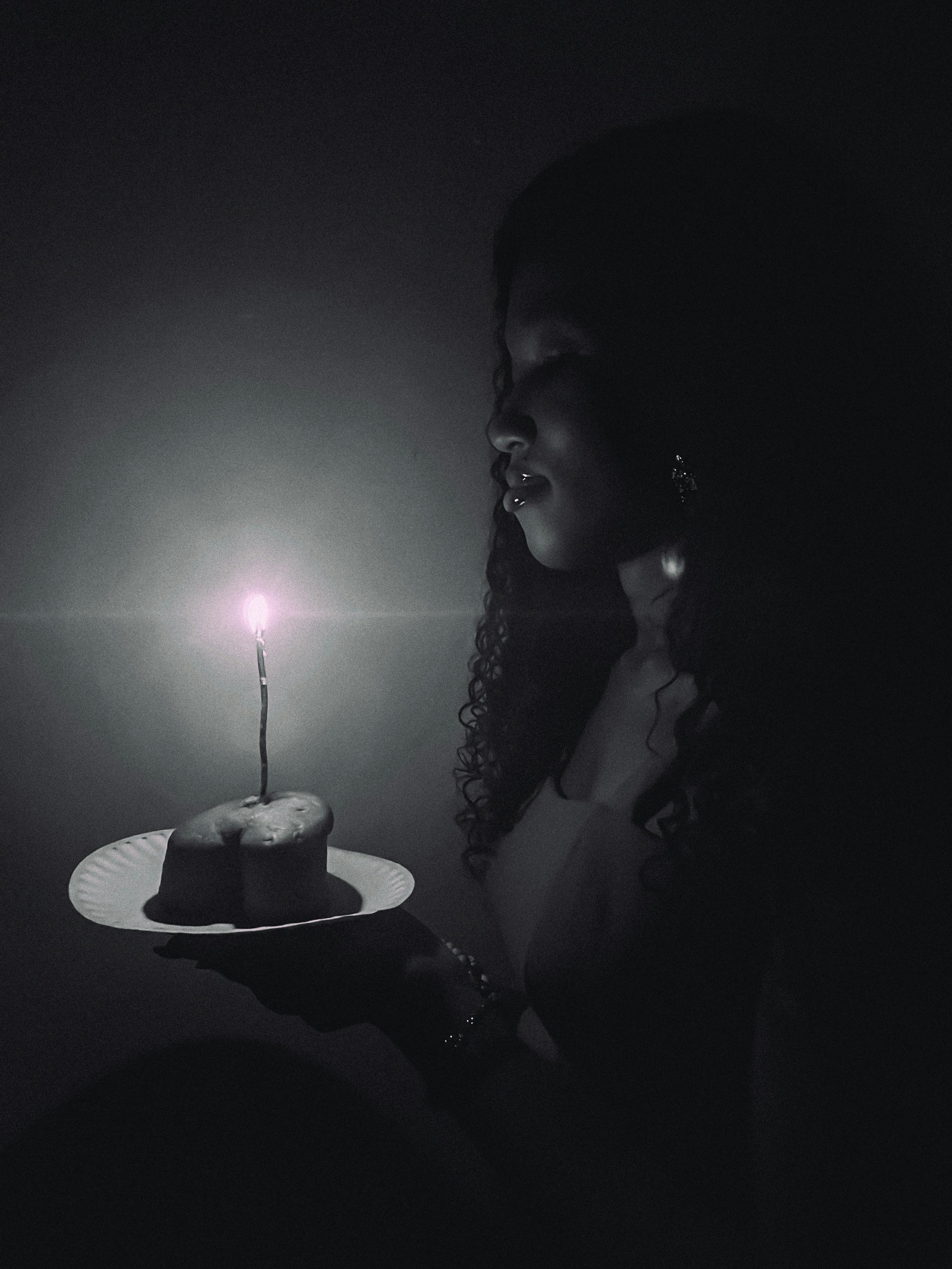 Gratis Foto suggestiva in bianco e nero di una donna che tiene in mano una torta di compleanno con le candeline accese. Foto a disposizione