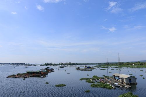 Free Floating houses on a calm river in Vietnam under a clear blue sky, showcasing serene rural life. Stock Photo