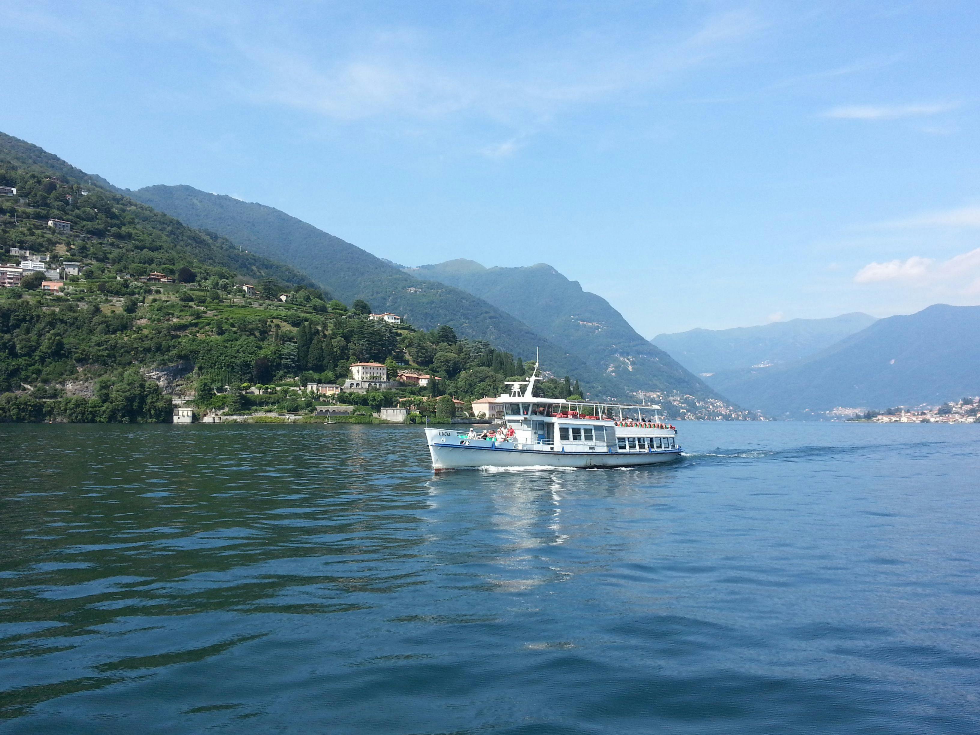 Boat navigating the deep blue-green waters of Lake Como with stunning views of Alpine mountains and charming Italian villages along the shoreline — the best way to explore Italy's most famous lake