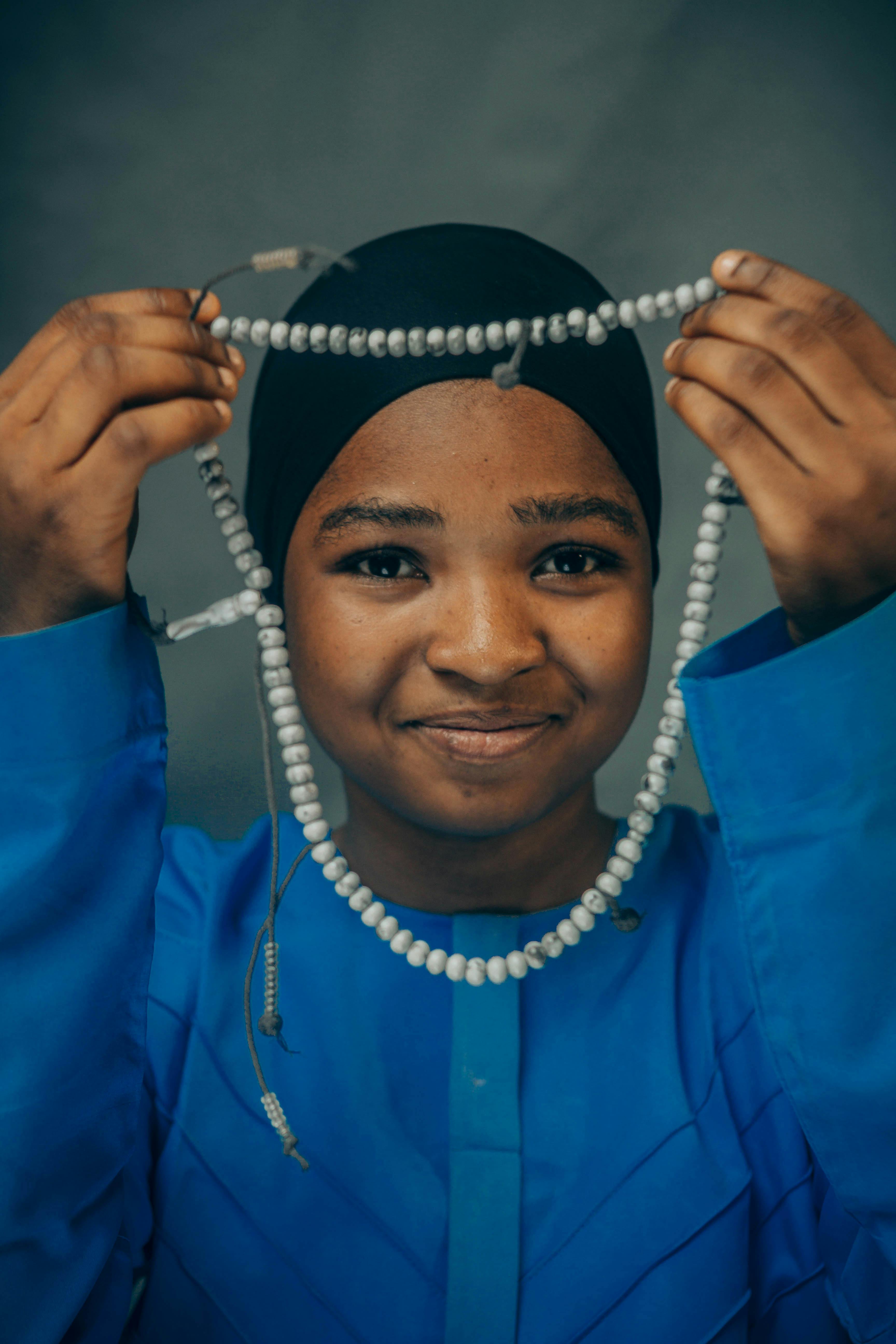 Ücretsiz Mavi kıyafet giymiş, elinde tesbih tutan gülümseyen kadın, Nijerya'da barış ve maneviyatı simgeliyor. Stok Fotoğraflar