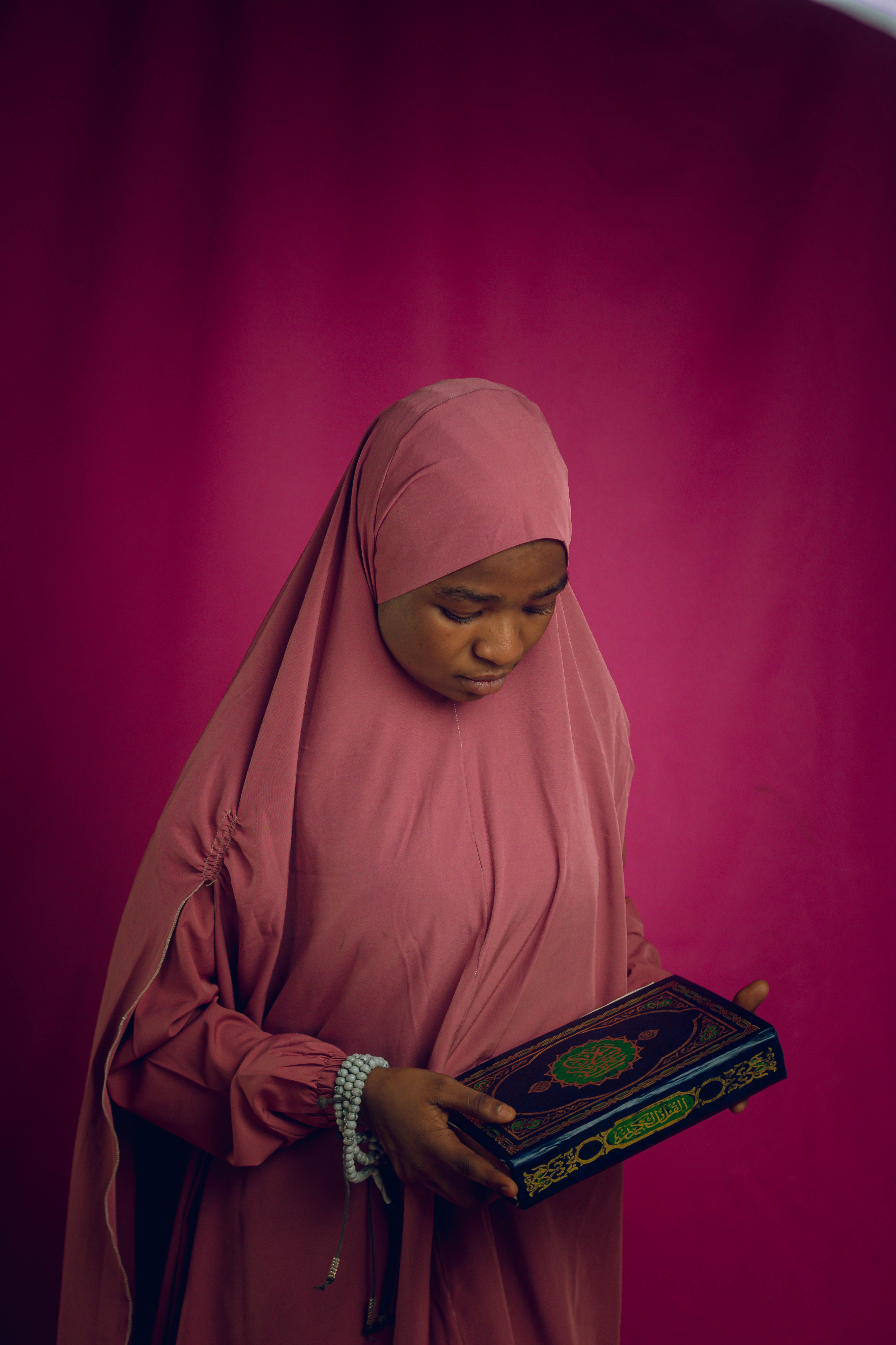 Young Woman in Hijab Holding Quran in Reflective Pose · Free Stock Photo