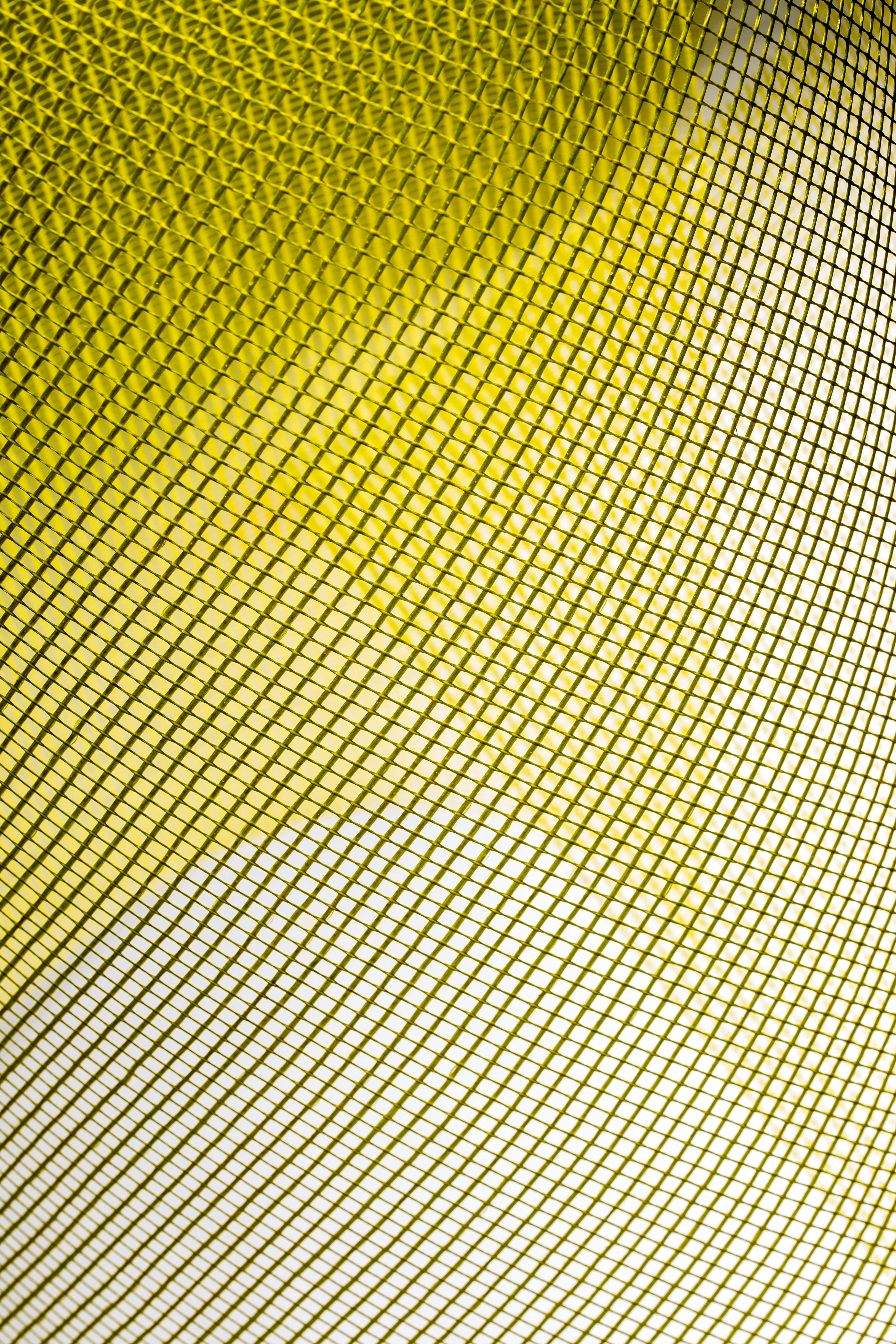 Free Close-up abstract texture of yellow mesh fabric with geometric pattern and vivid lighting. Stock Photo