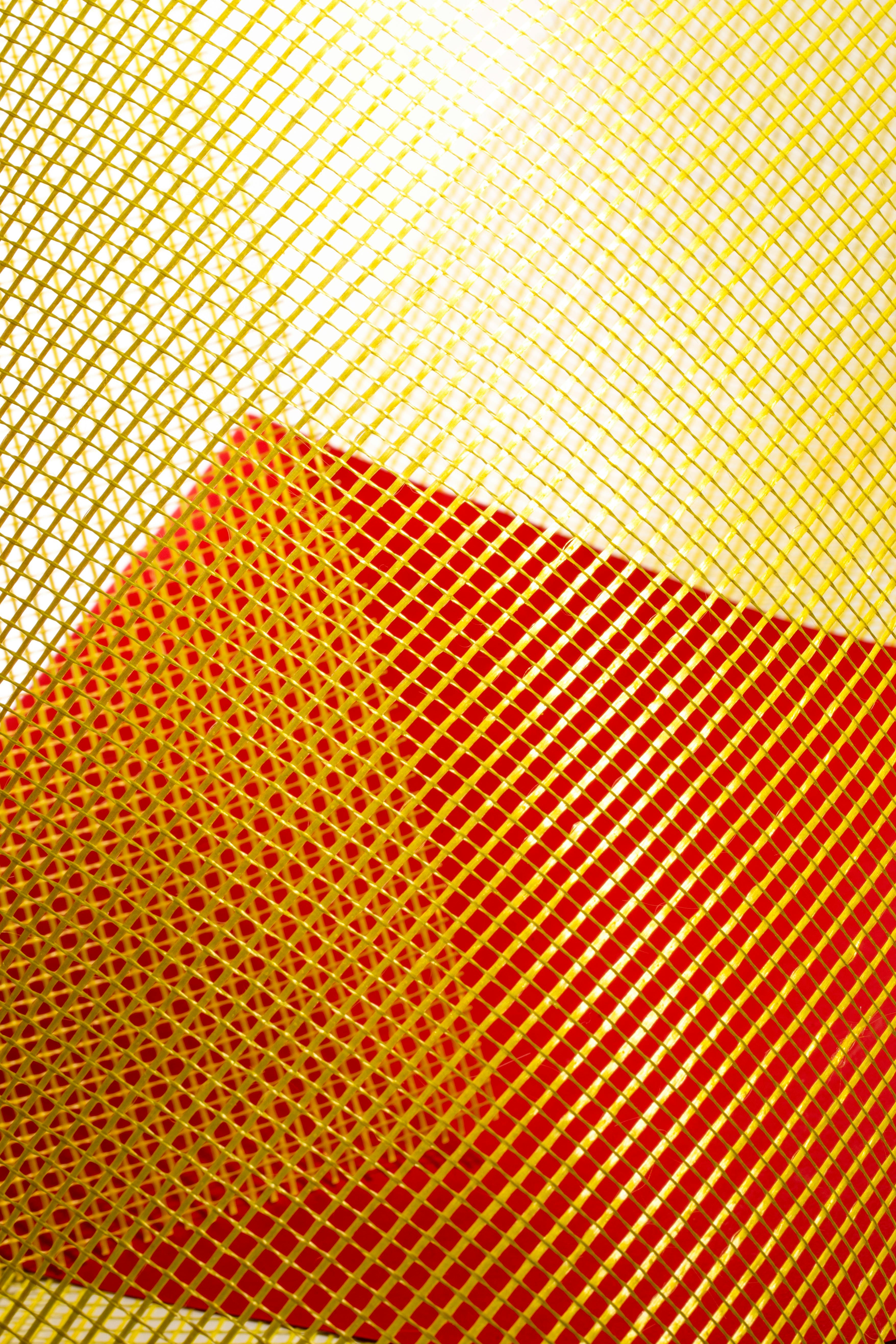 Free Vibrant abstract image featuring intersecting yellow and red mesh patterns creating dynamic visual tension. Stock Photo
