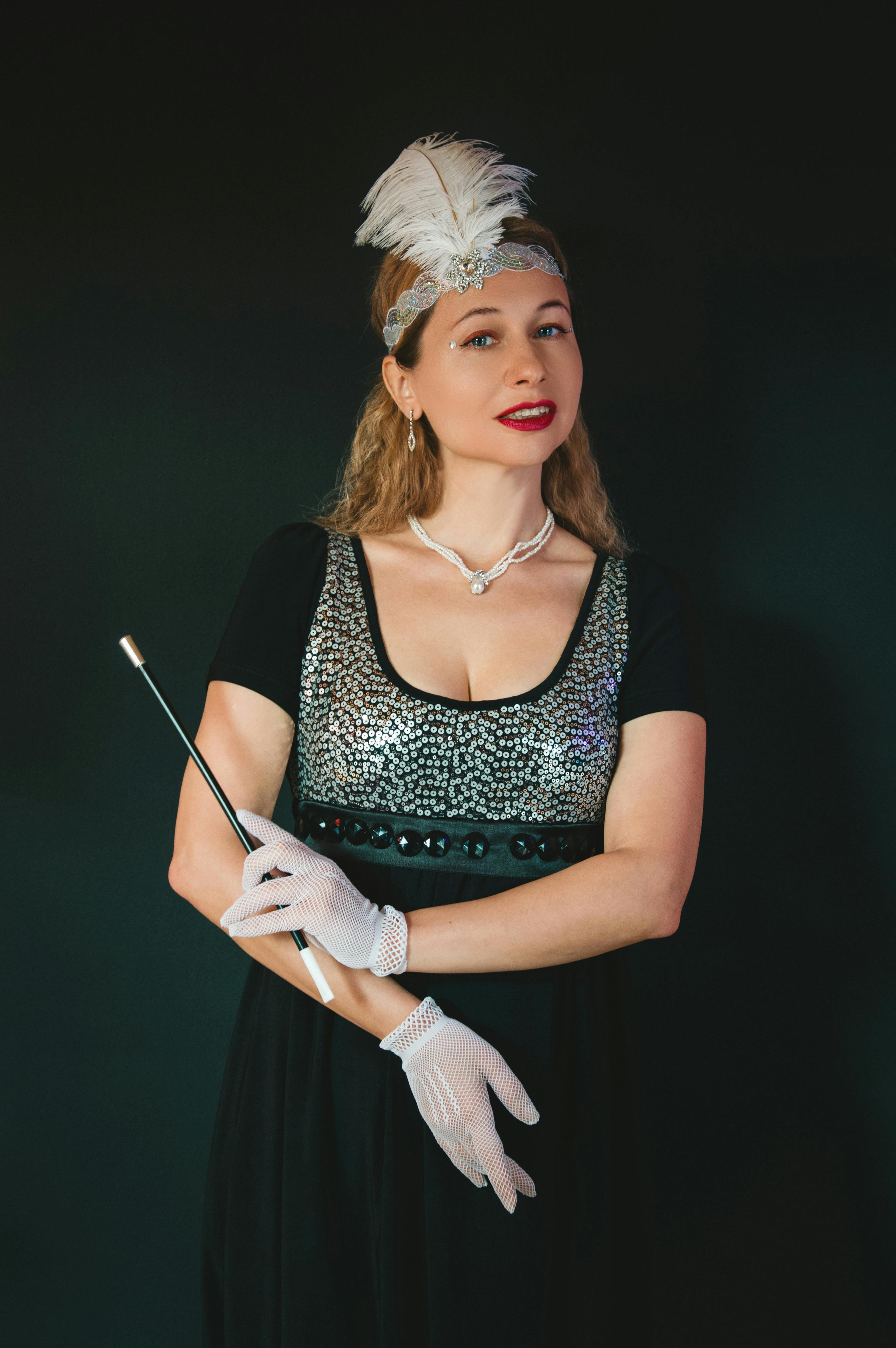 Gratis Portræt af en kvinde i vintage 1920'er-tøj med pailletkjole, fjerbesat hovedbeklædning og elegante handsker. Lagerfoto
