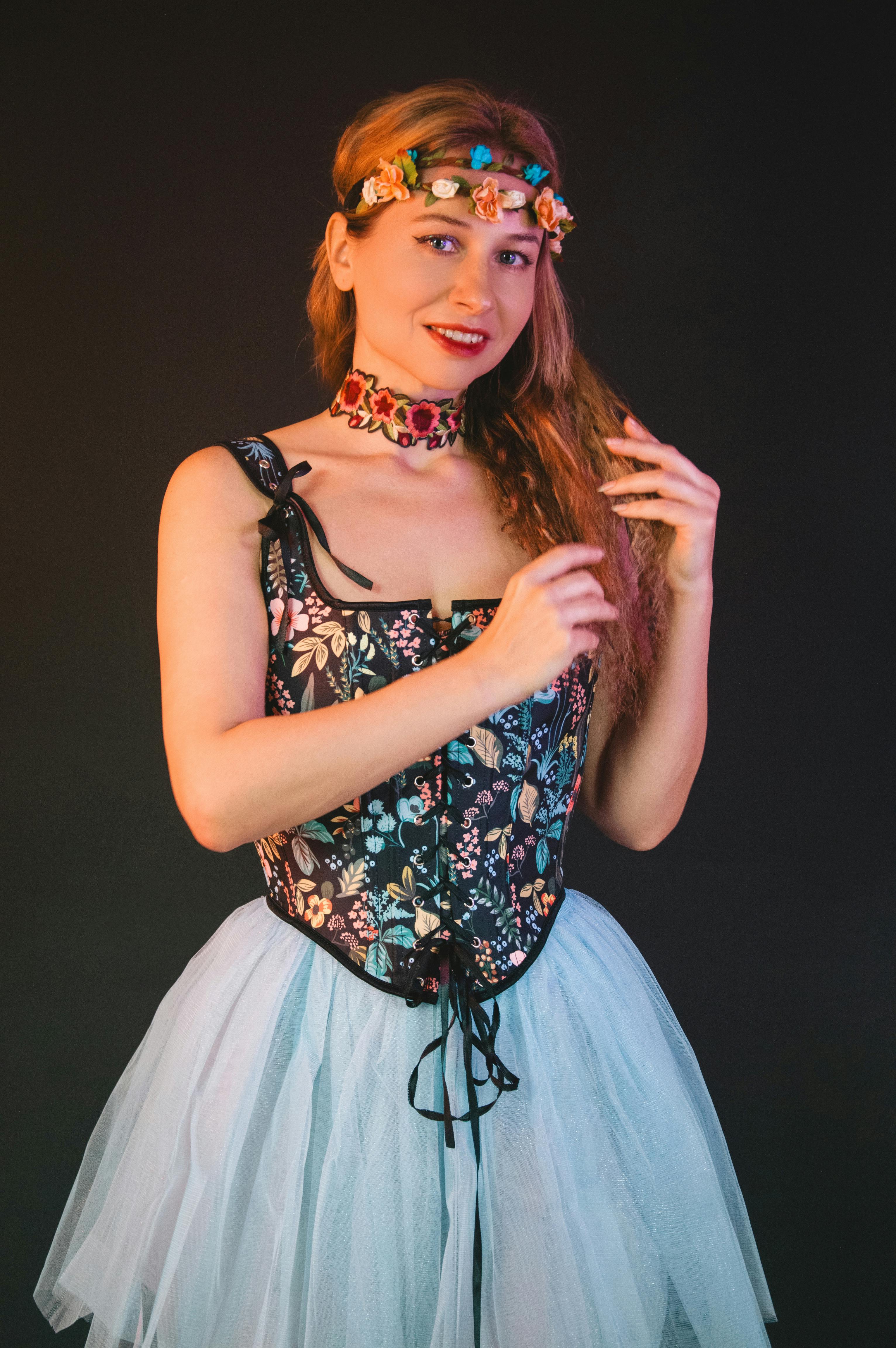 Kostnadsfria En kvinna klädd i ett blommigt livstycke och tyllkjol prydd med en blomsterkrona och ett blommigt choker. Stock foto