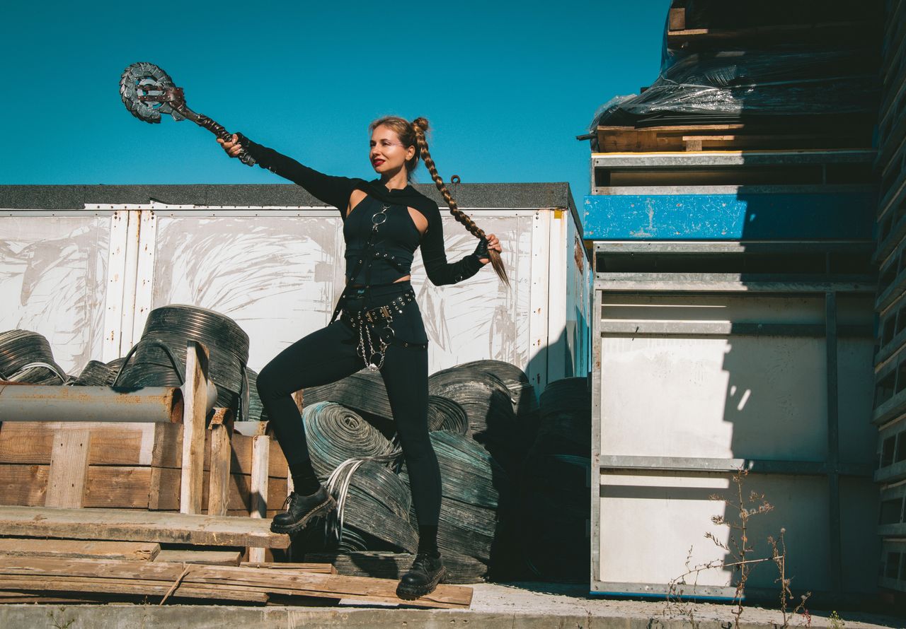 a woman dressed in a warrior costume poses outdoors with braided hair