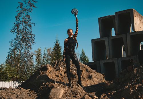 Free A strong female warrior character stands confidently holding a weapon in a construction site setting. Stock Photo