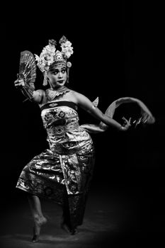Black and white portrait of a Balinese dancer in intricate traditional attire performing.