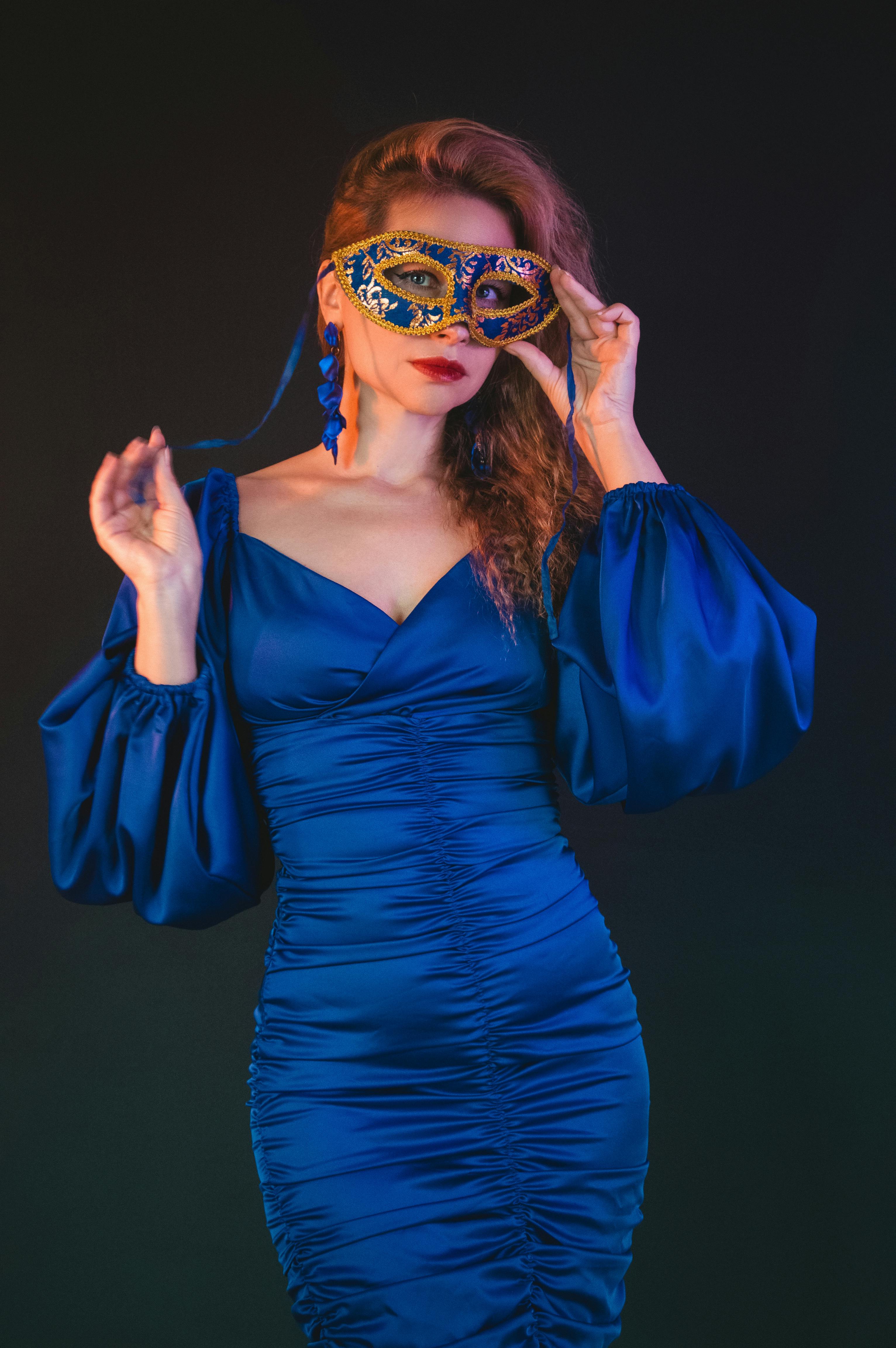 gratis Een stijlvolle vrouw in een blauwe jurk, met een Venetiaans masker in haar hand, straalt elegantie en mysterie uit. Stockfoto