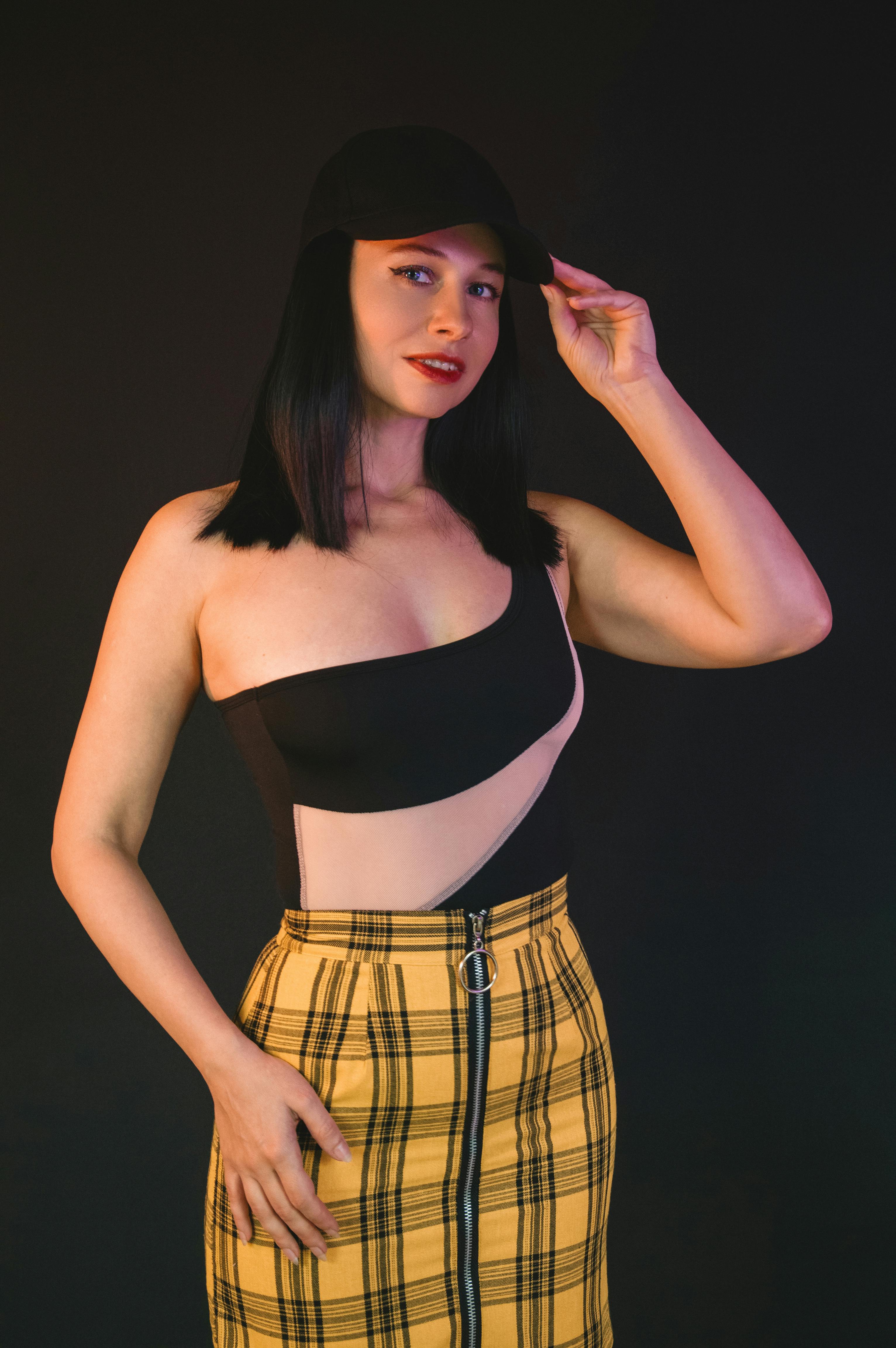 Gratis Mujer segura de sí misma con un atuendo moderno posando sobre un fondo oscuro. Foto de stock