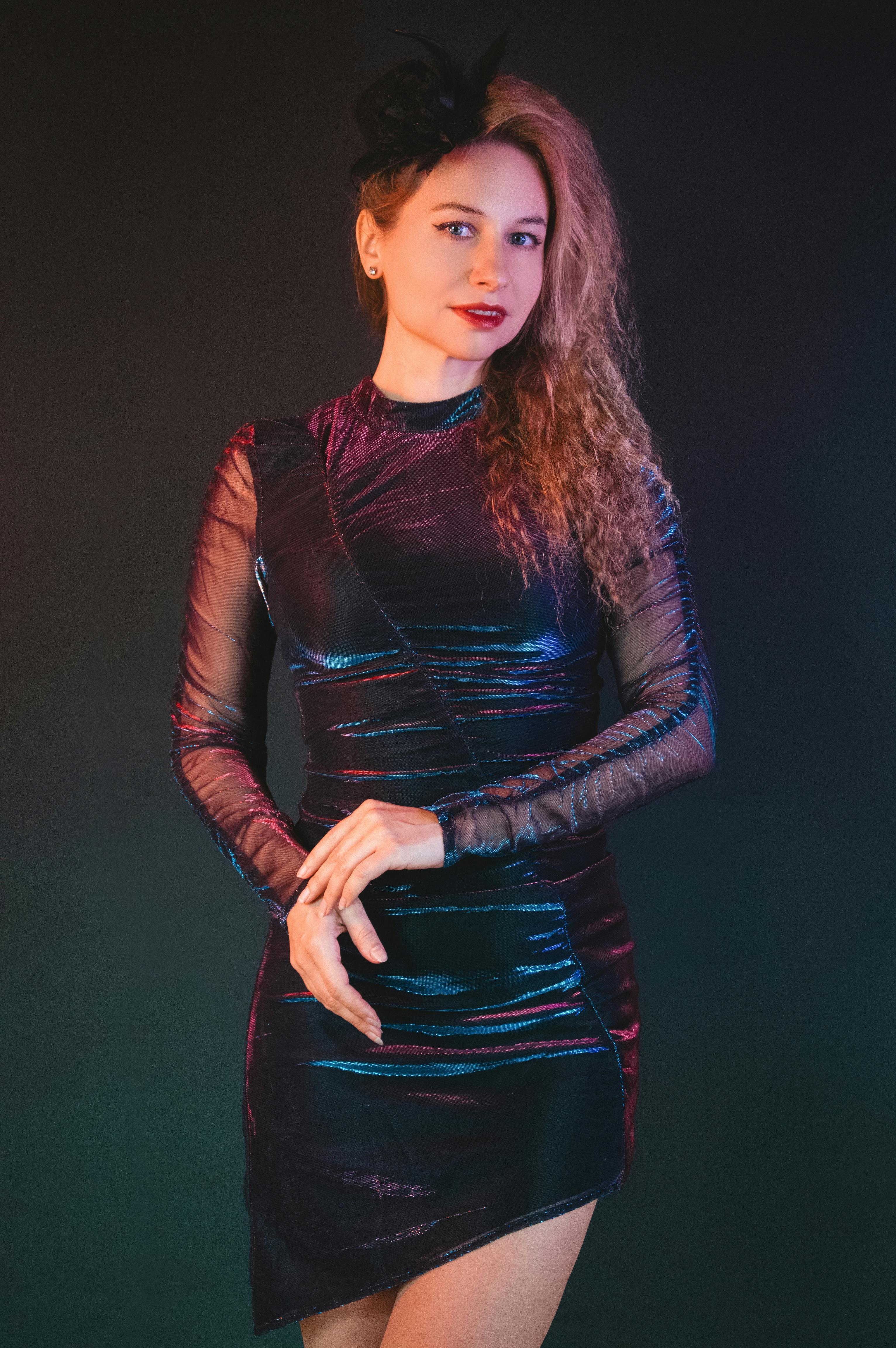 Gratis Moderigtig kvinde poserer i en elegant, mørk, glitrende aftenkjole mod en mørk studiebaggrund. Lagerfoto