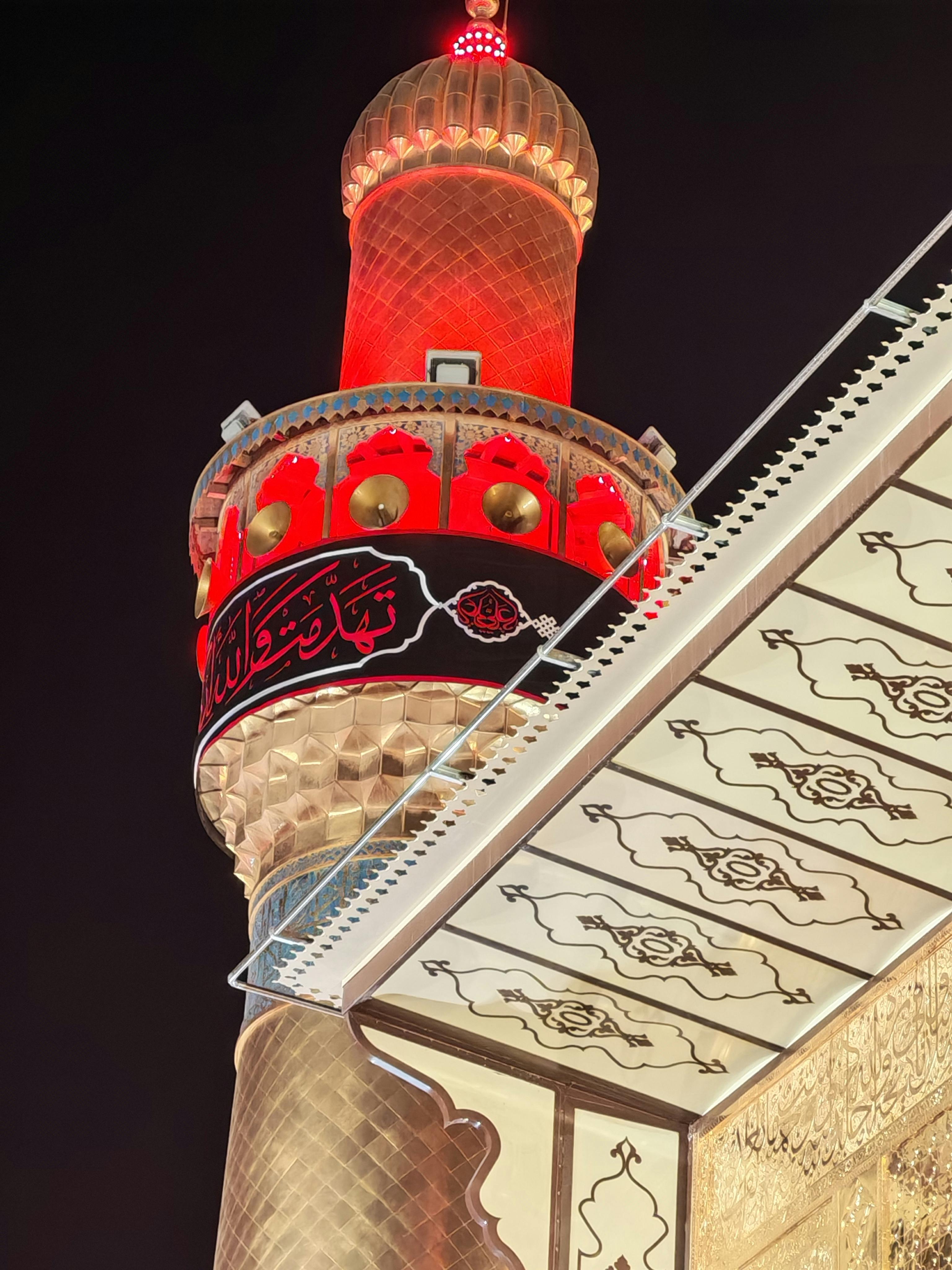A beautifully lit minaret in Najaf, Iraq, captured at night showcasing intricate Islamic architecture.