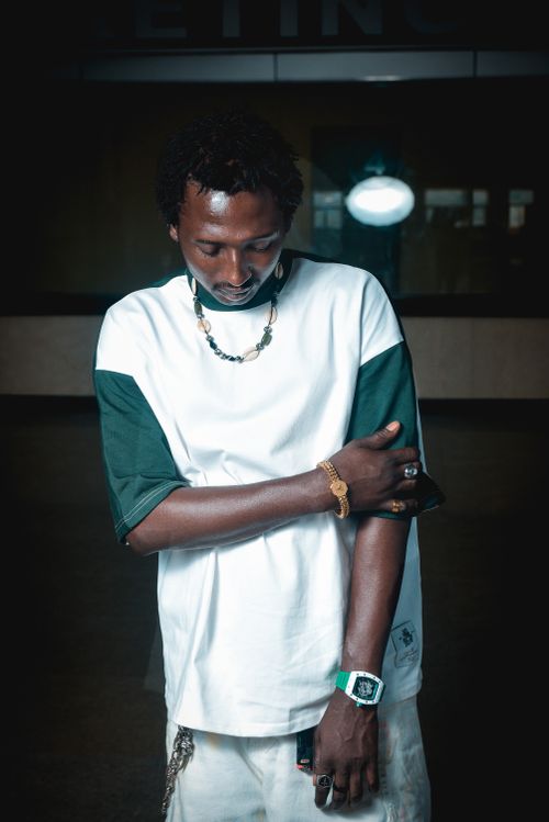 Free Man posing indoors in casual green and white outfit with accessories. Stock Photo