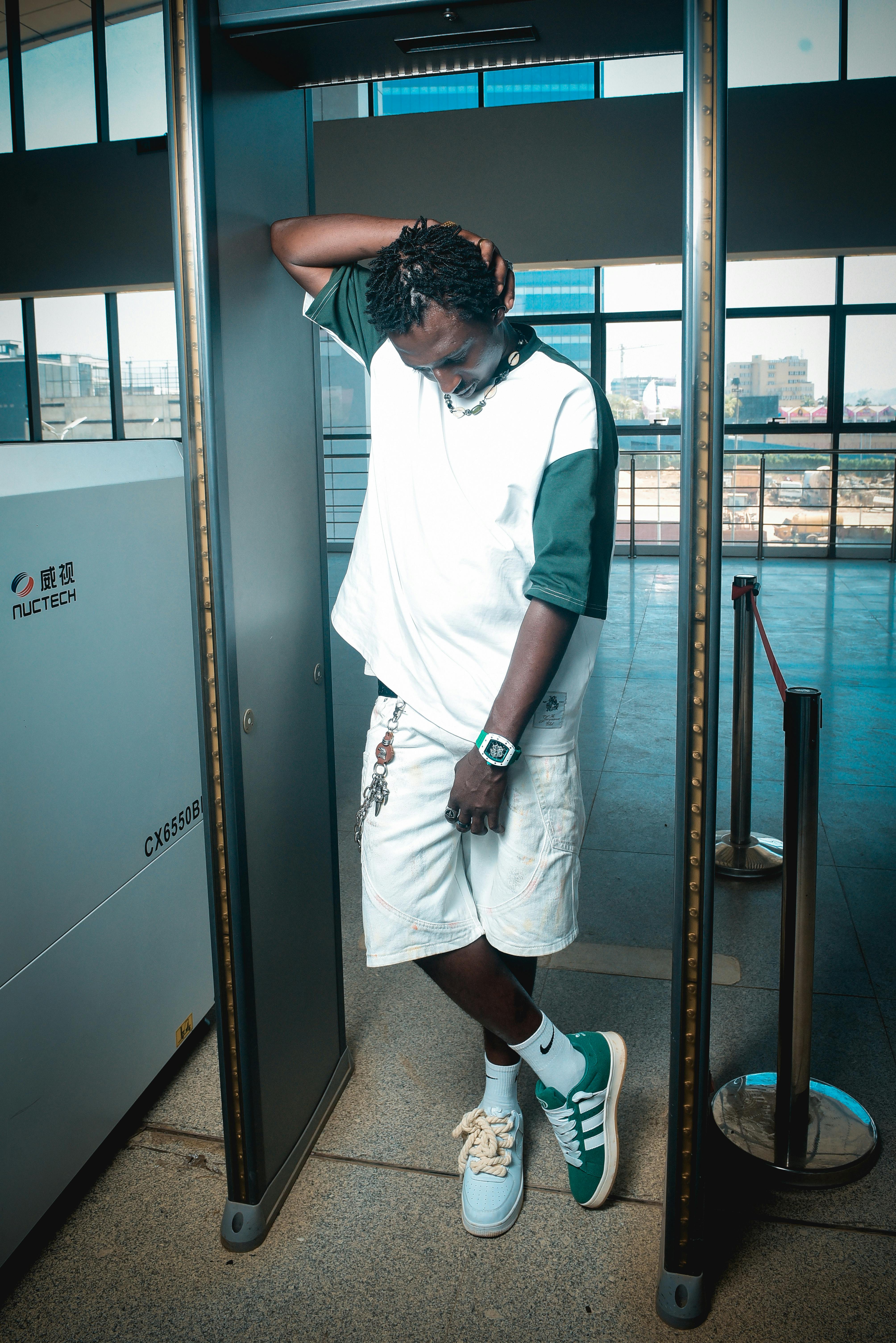 Young man at airport security screening relaxed in casual attire.