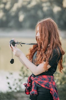 一名年轻的红发女子在户外手持相机，捕捉大自然的美丽