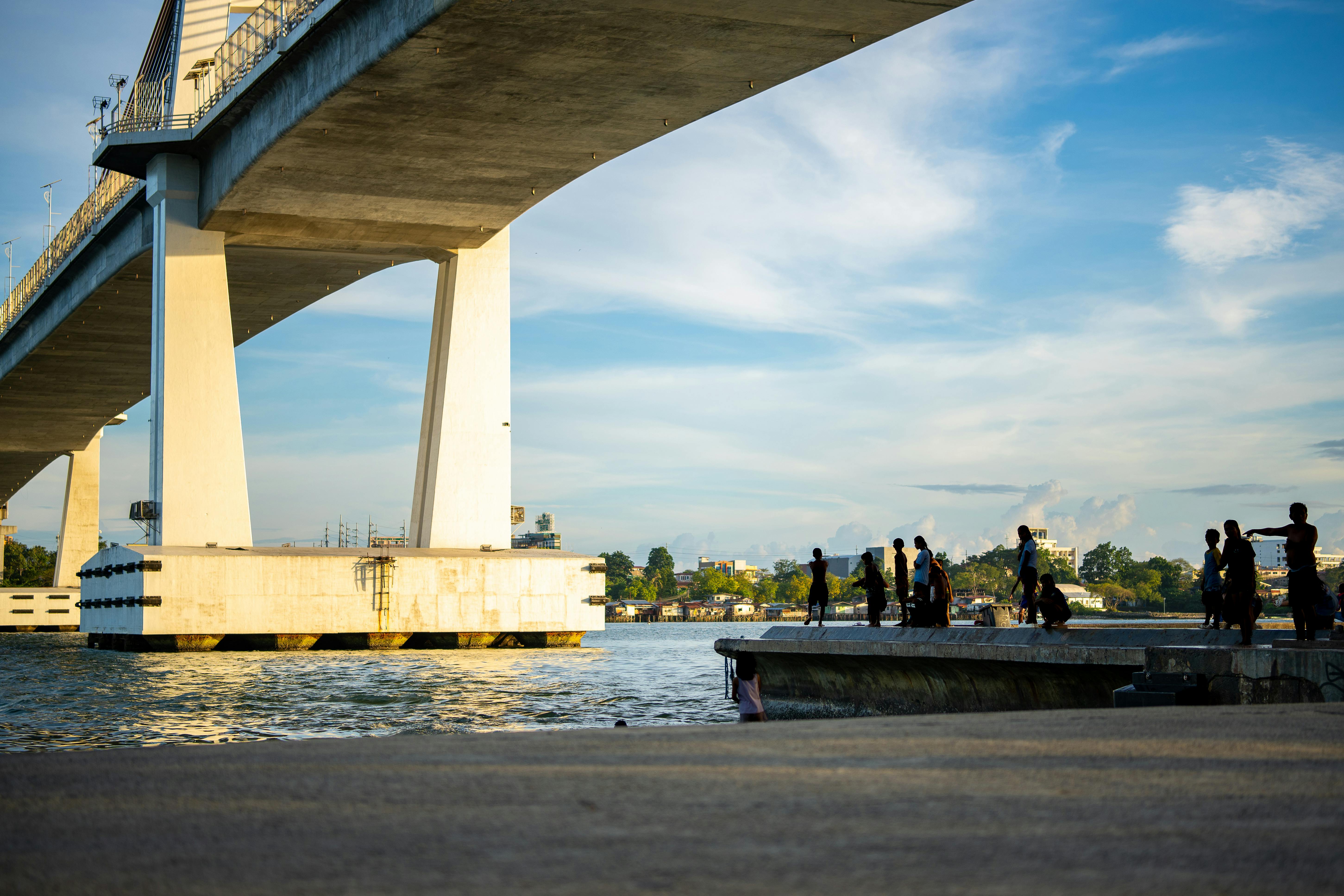 Gratis Bambini che nuotano e giocano sotto il ponte Marcelo Fernan al tramonto a Mandaue, Filippine. Foto a disposizione