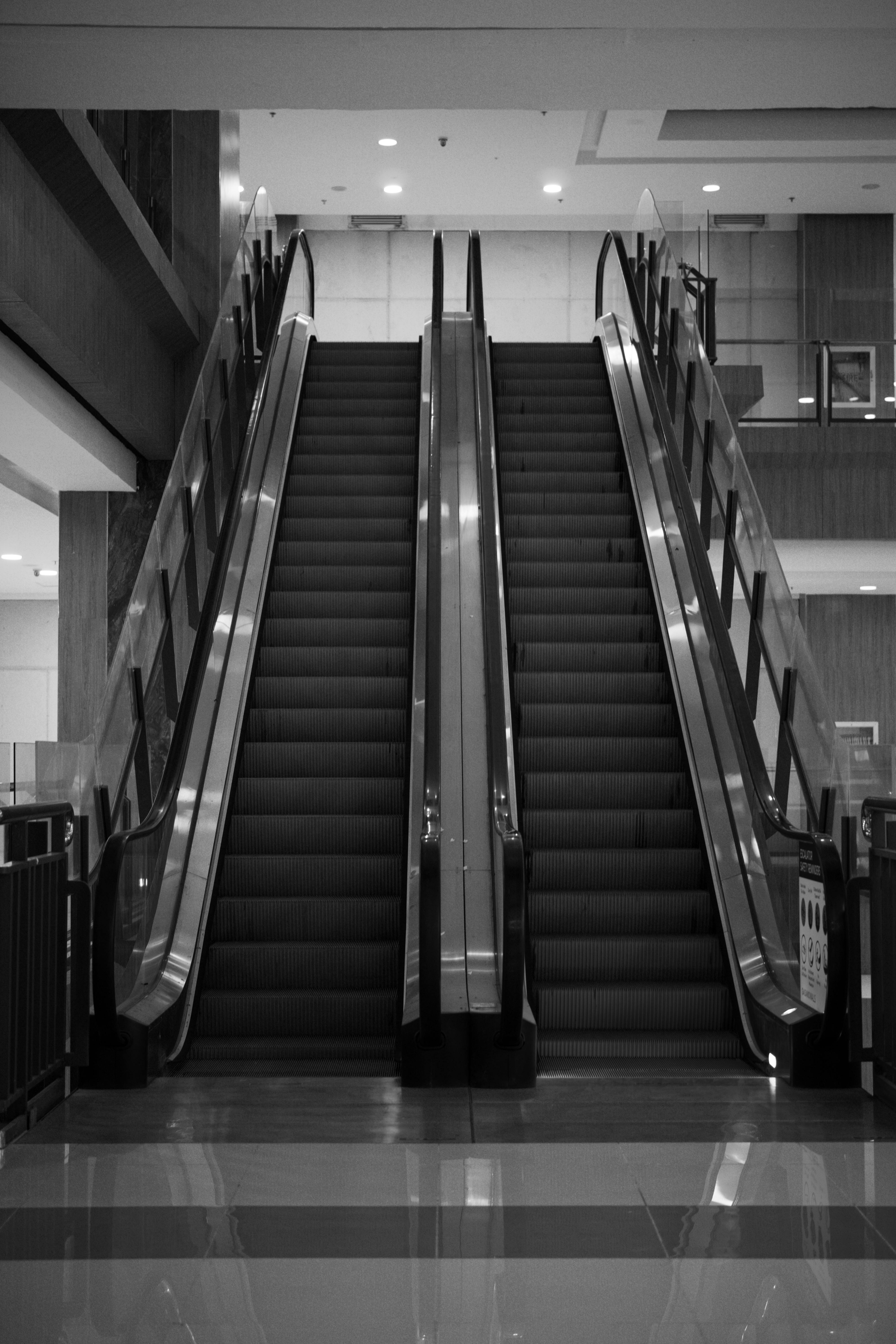 Kostenlos Symmetrische Rolltreppen im Inneren eines modernen Einkaufszentrums, die minimalistische Architektur demonstrieren. Stock-Foto