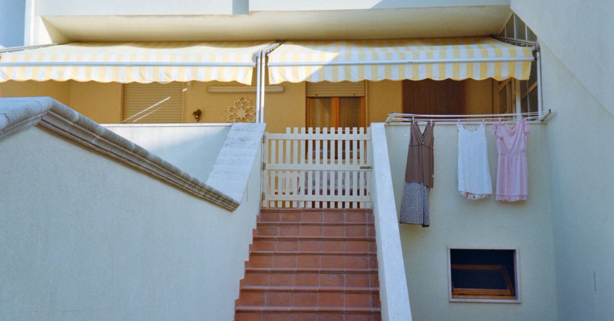 Outdoor staircase with laundry drying under a striped awning, featuring a cozy balcony scene.