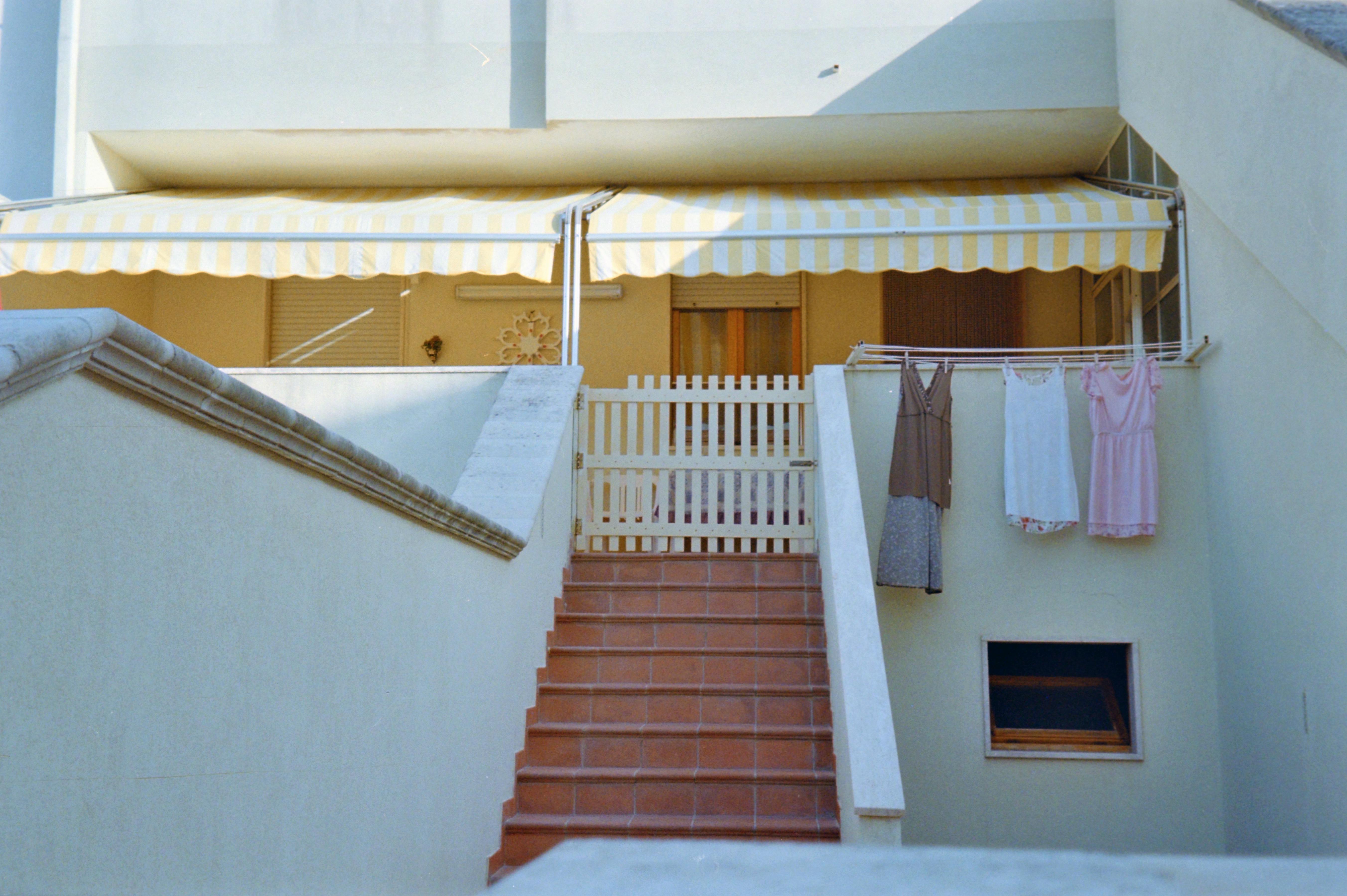 Free Outdoor staircase with laundry drying under a striped awning, featuring a cozy balcony scene. Stock Photo