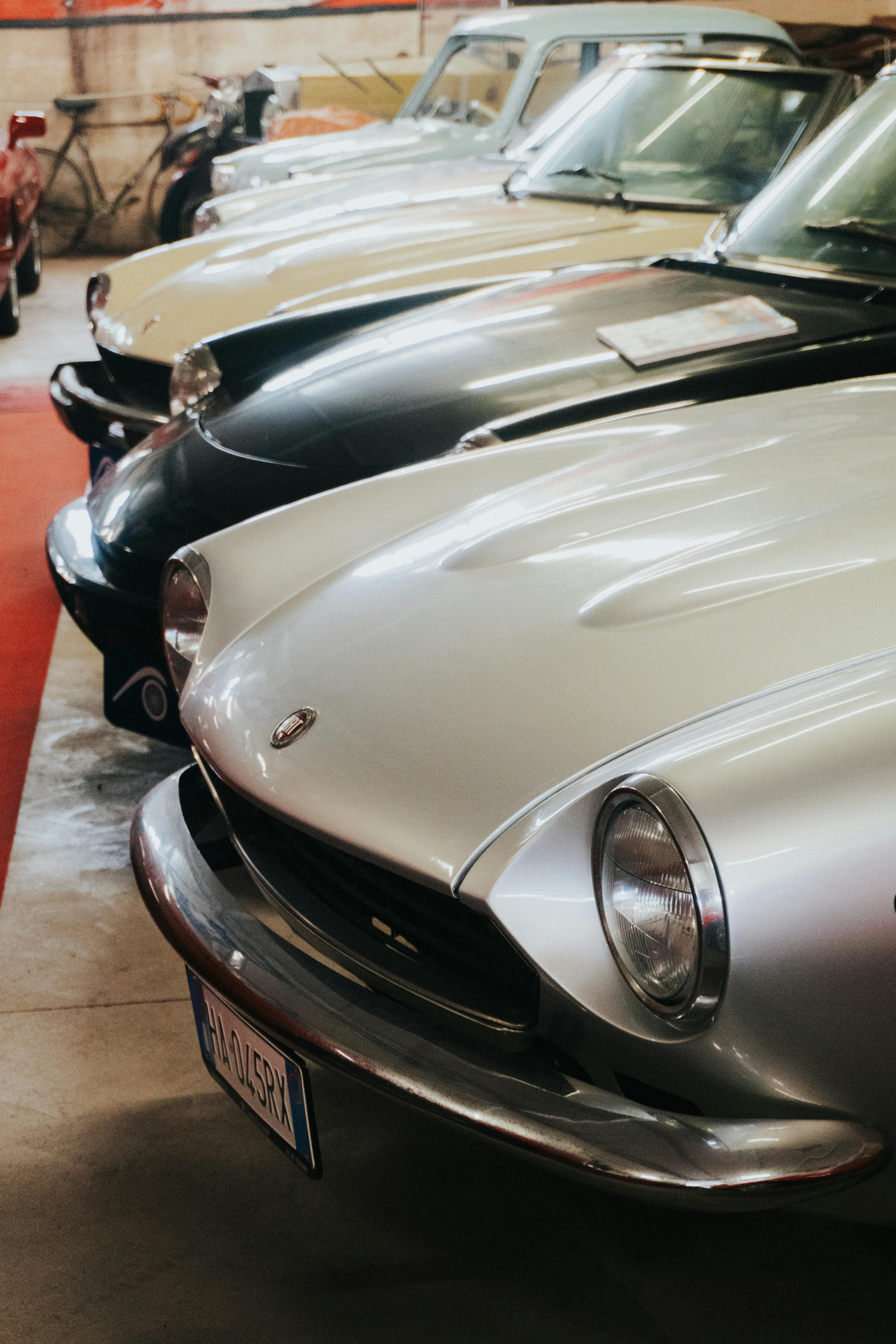Lineup of classic cars displayed in an indoor showroom setting, showcasing vintage automotive style.