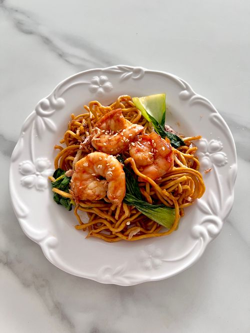 Free A delicious serving of shrimp stir-fried noodles with vegetables on a decorative white plate. Stock Photo