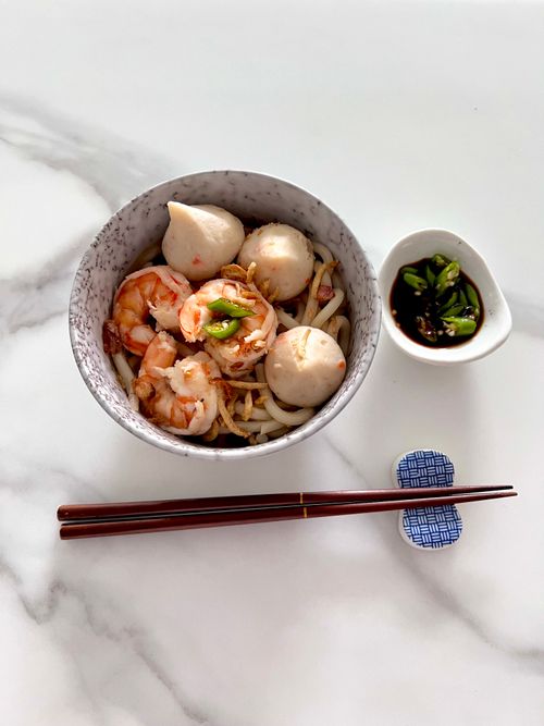 Free Appetizing seafood udon bowl with shrimp, fish balls, and dipping sauce on a marble surface. Stock Photo