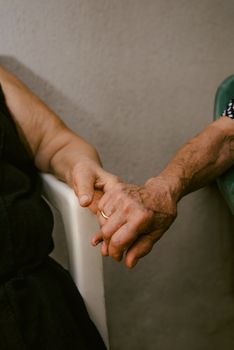 Close-up of elderly couple's hands clasped, representing love and companionship.