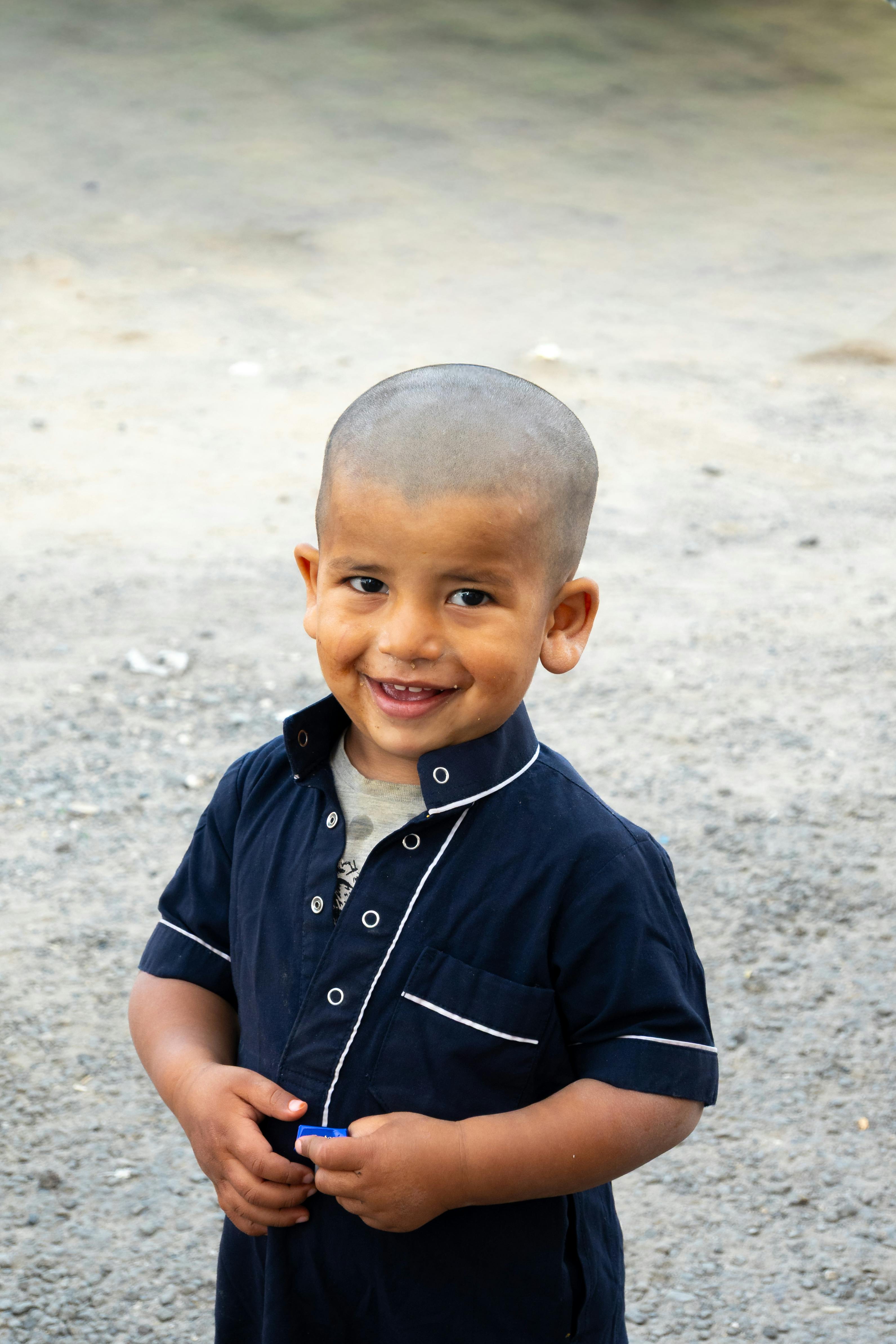 bezplatná Roztomilé dítě se zářivě usmívá, když stojí venku za slunečného dne. Základová fotografie