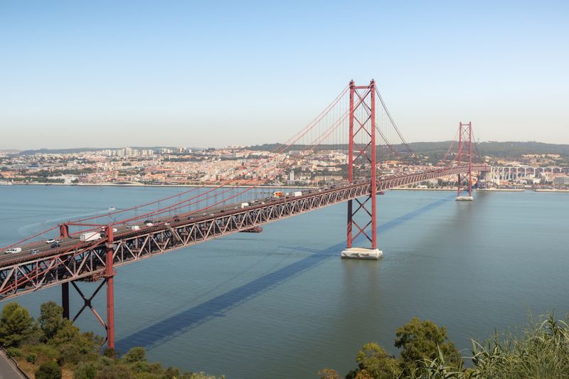 The red 25 de Abril suspension bridge spanning the Tagus river in Lisbon on a hazy day.
