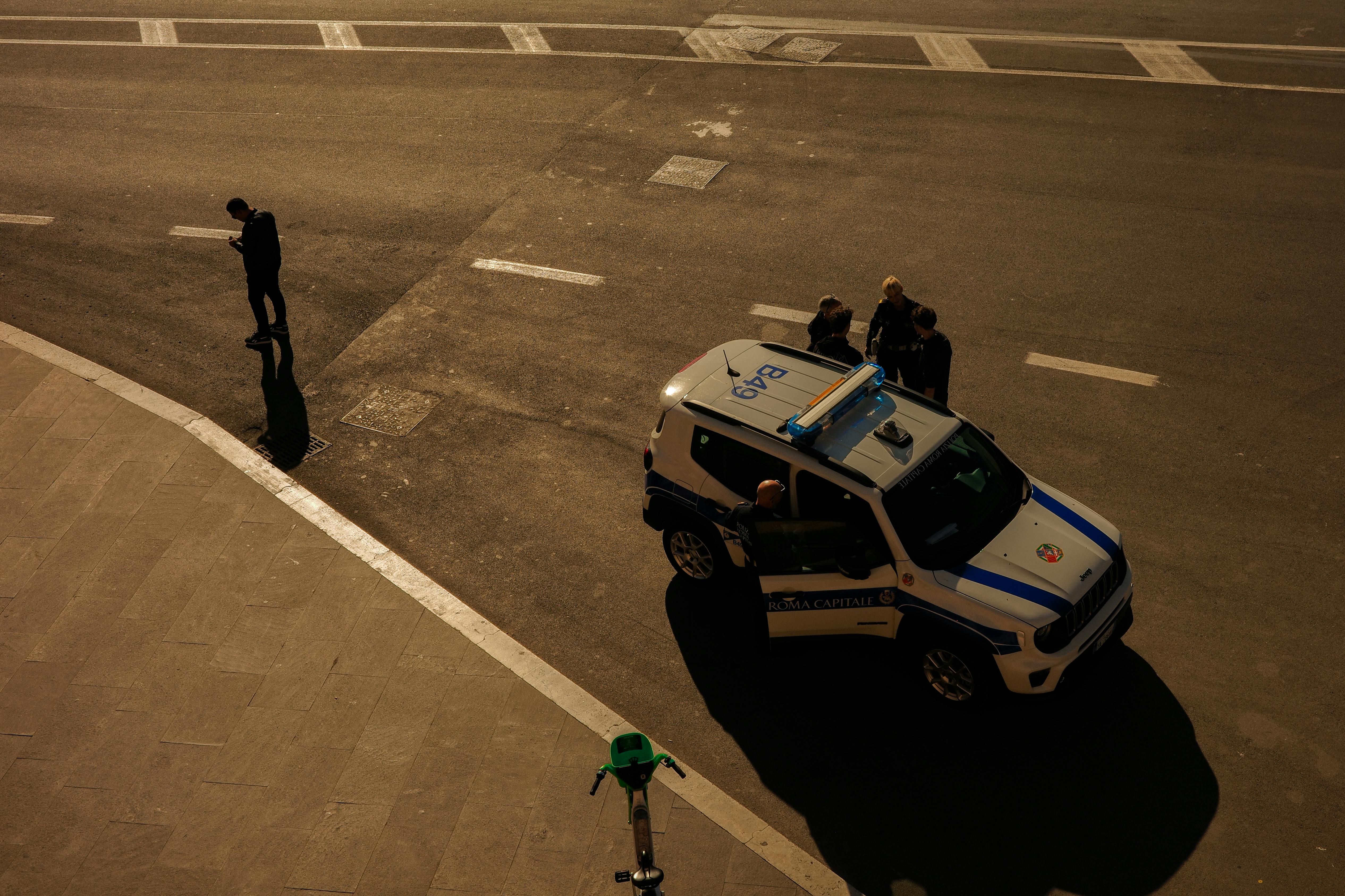 bezplatná Pohled z vysokého úhlu na policejní auto v ulicích Říma v Itálii, kde se kolem něj pohybují lidé. Základová fotografie