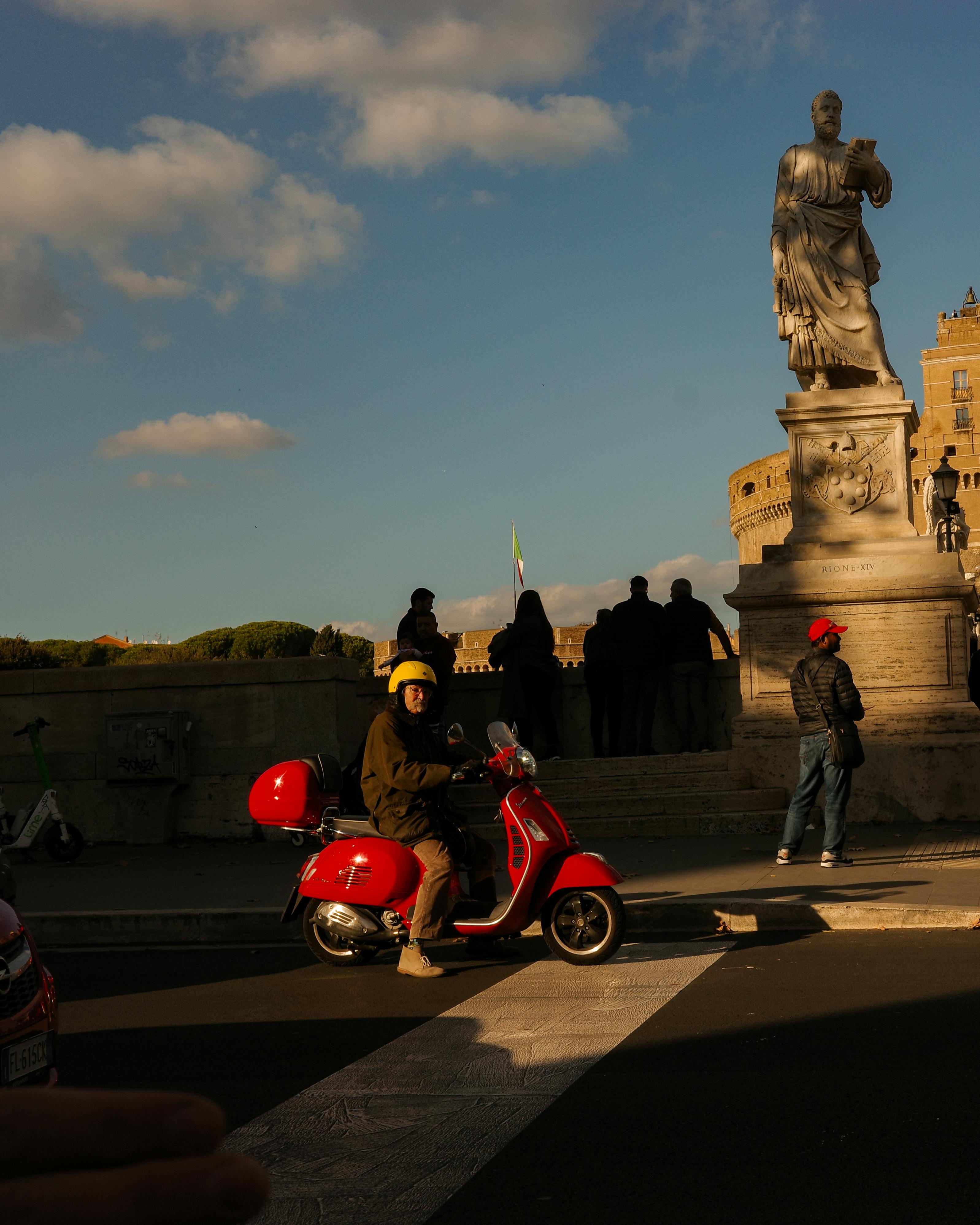 gratis Straatbeeld in Rome met een scooter en een iconisch standbeeld in het warme avondlicht. Stockfoto