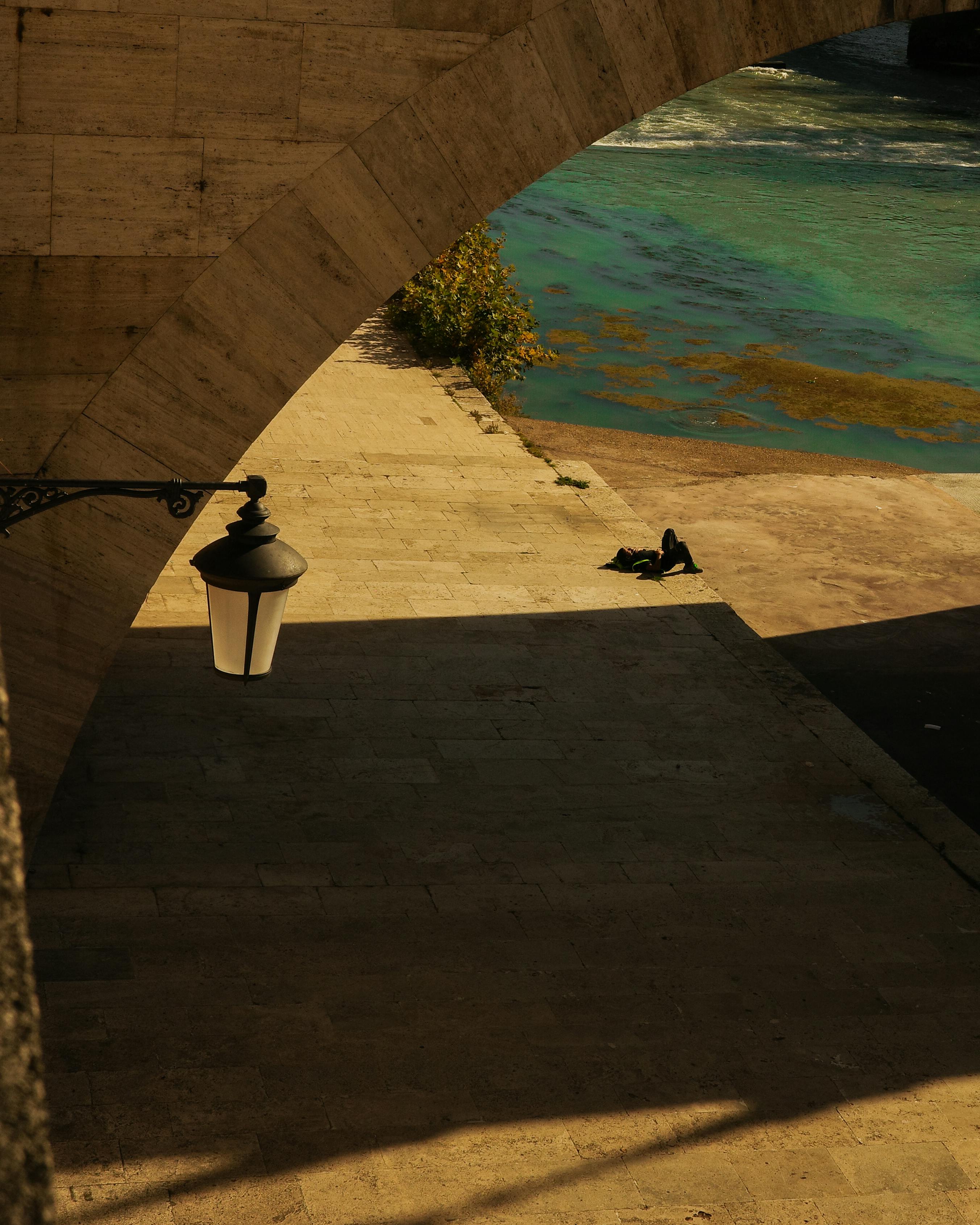 無料 イタリア、ラツィオ州の橋の下にある、柔らかな陽光に照らされた静かな川岸の眺め。 写真素材