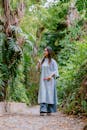 Woman in Blue Dress Walking in a Green Forest Pathway