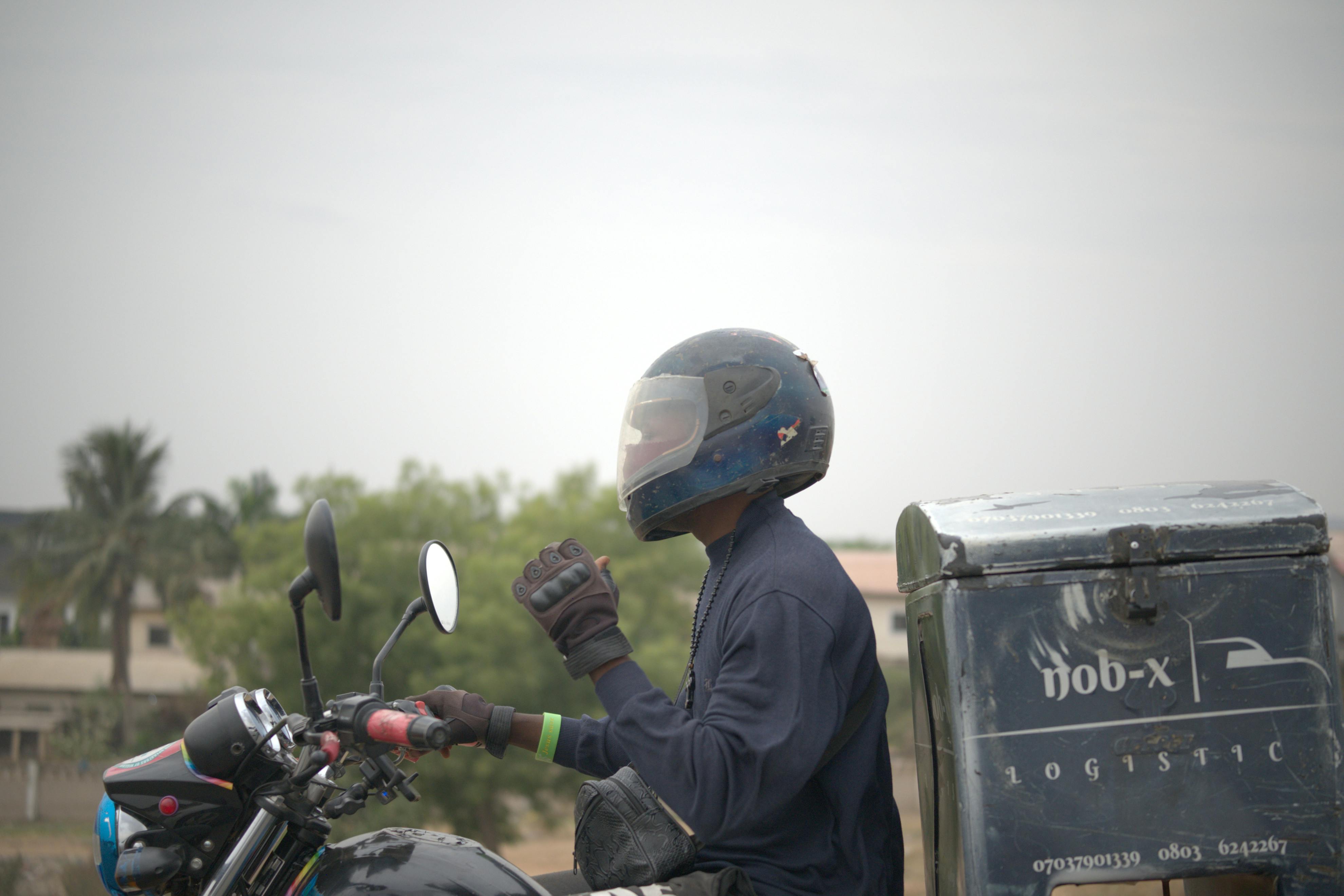 Gratuit Livreur à moto au Nigéria, portant un équipement de protection et un casque. Photos