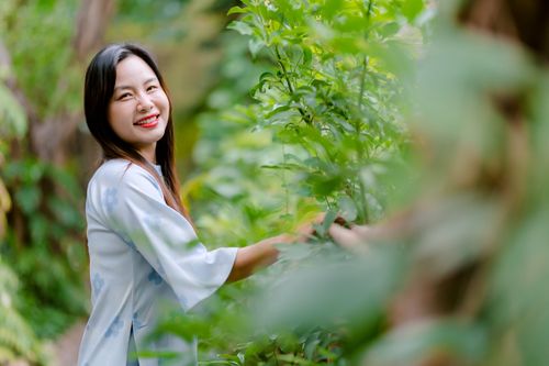 Free Happy woman in blue kimono smiling amidst lush greenery outdoors. Stock Photo