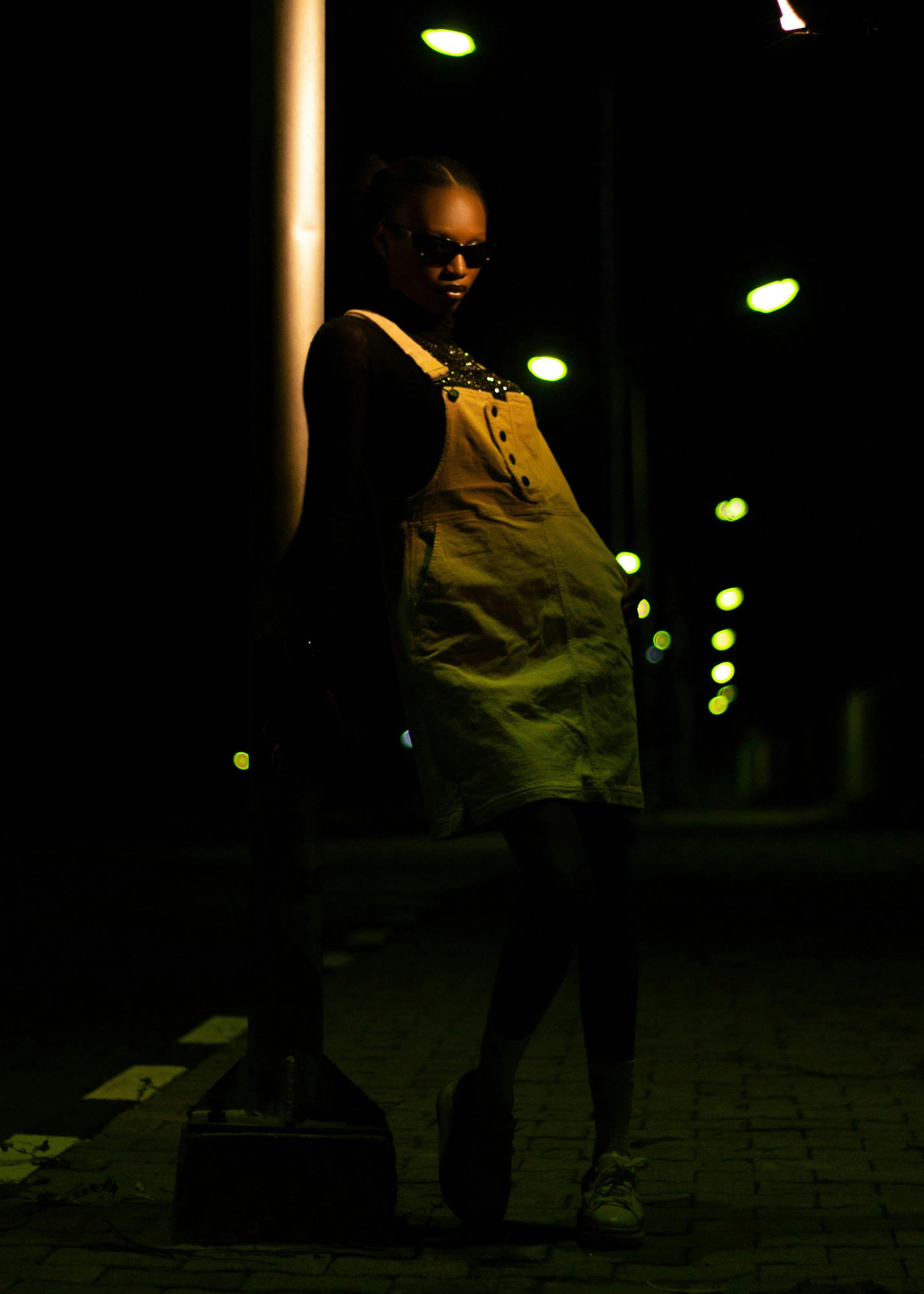 Безкоштовне Стильна жінка біля вуличного ліхтаря в нічній сцені. Міська мода та настрій поєднання. стокове фото