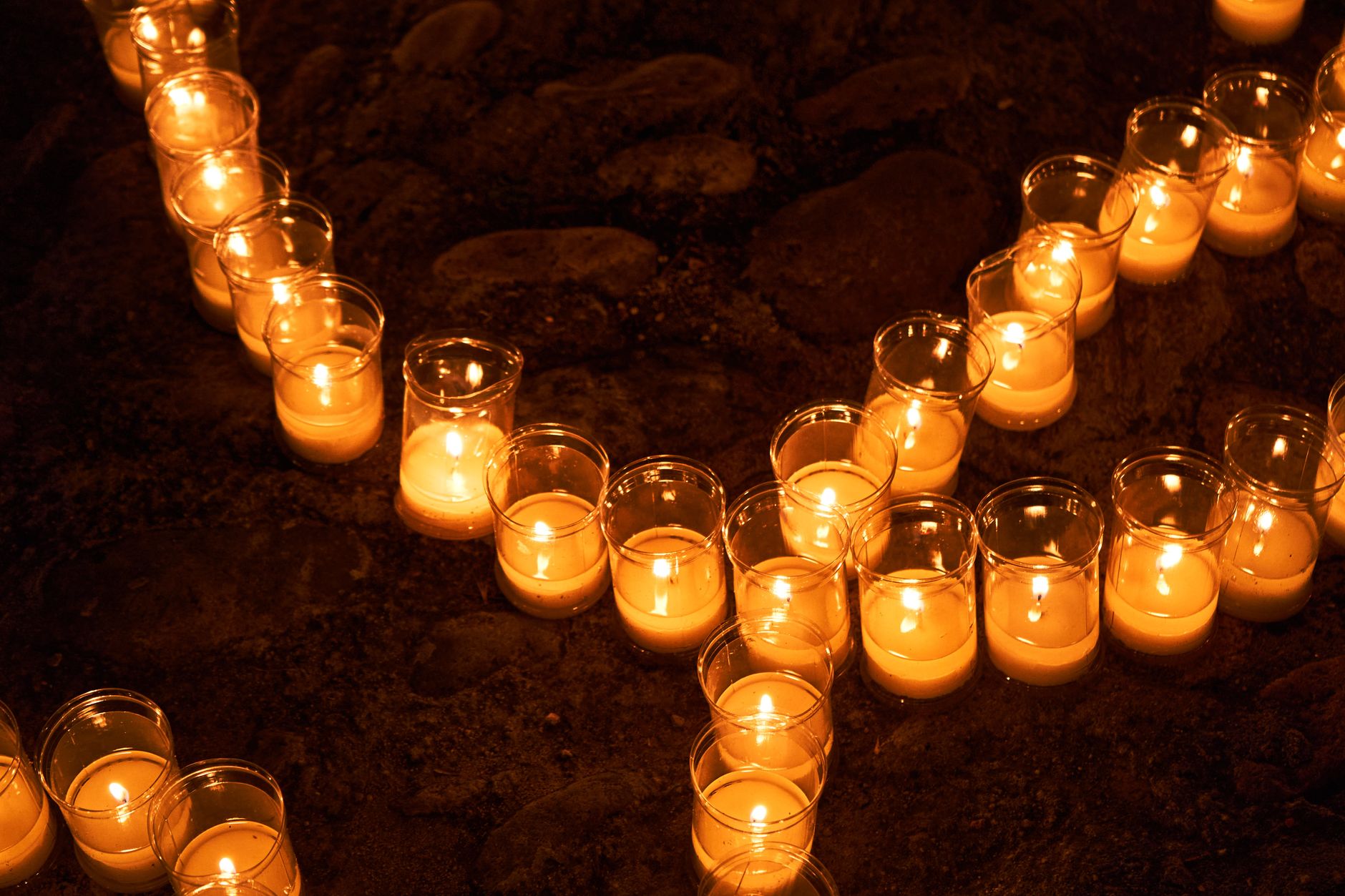 Velas acesas em potes de vidro sobre uma mureta de cobertura ao anoitecer de verão