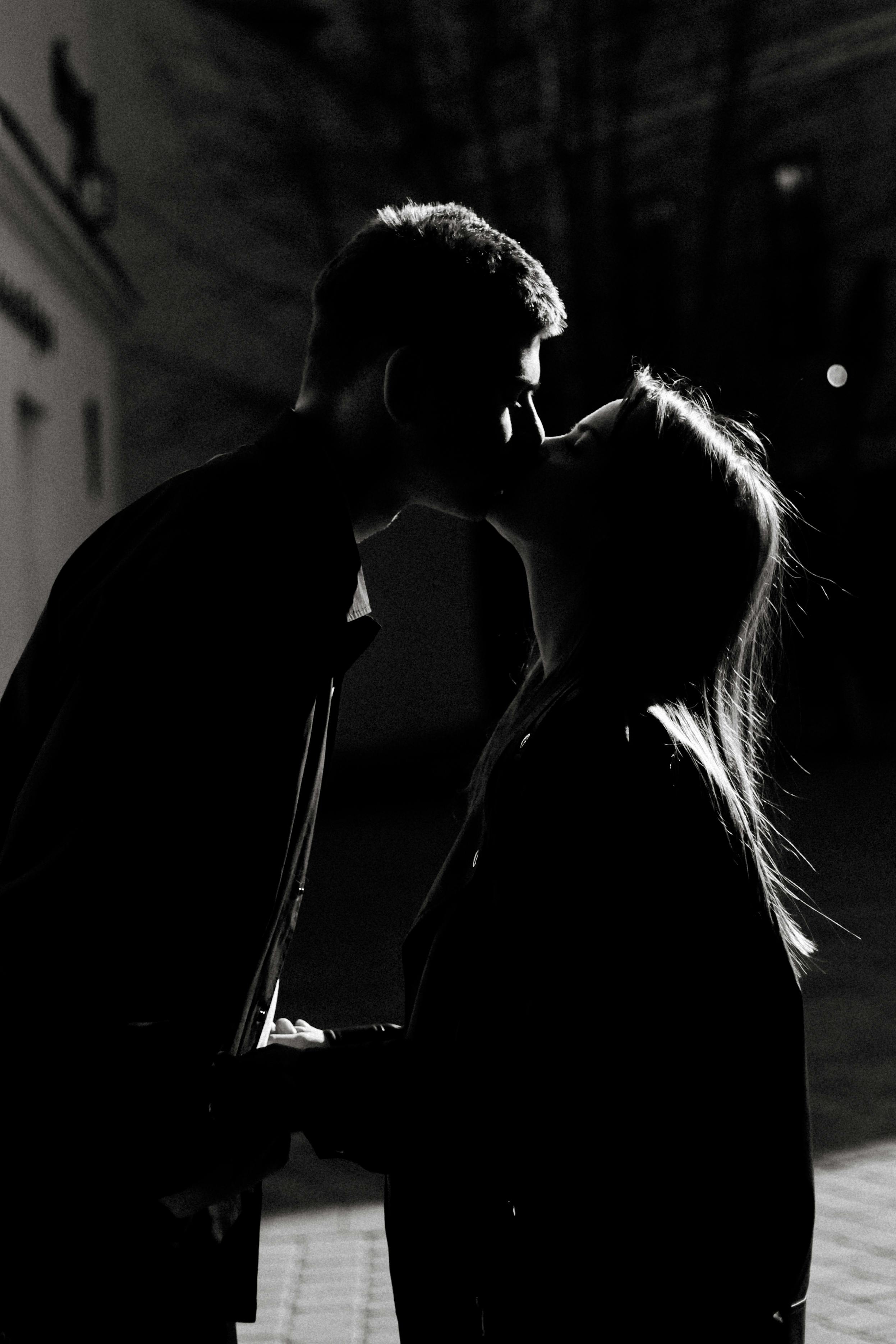 gratis Zwart-wit silhouet van een stel dat 's nachts buiten kust, wat romantiek en intimiteit uitstraalt. Stockfoto