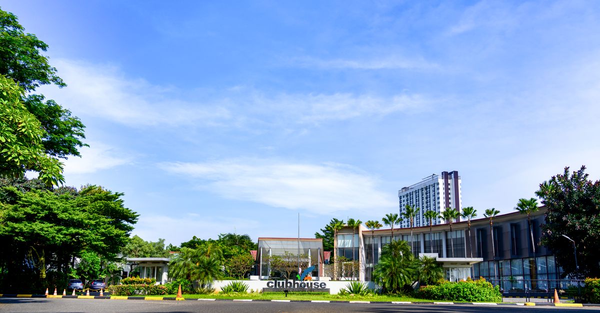 Contemporary clubhouse surrounded by lush greenery on a sunny day, suitable for resort or real estate concepts.