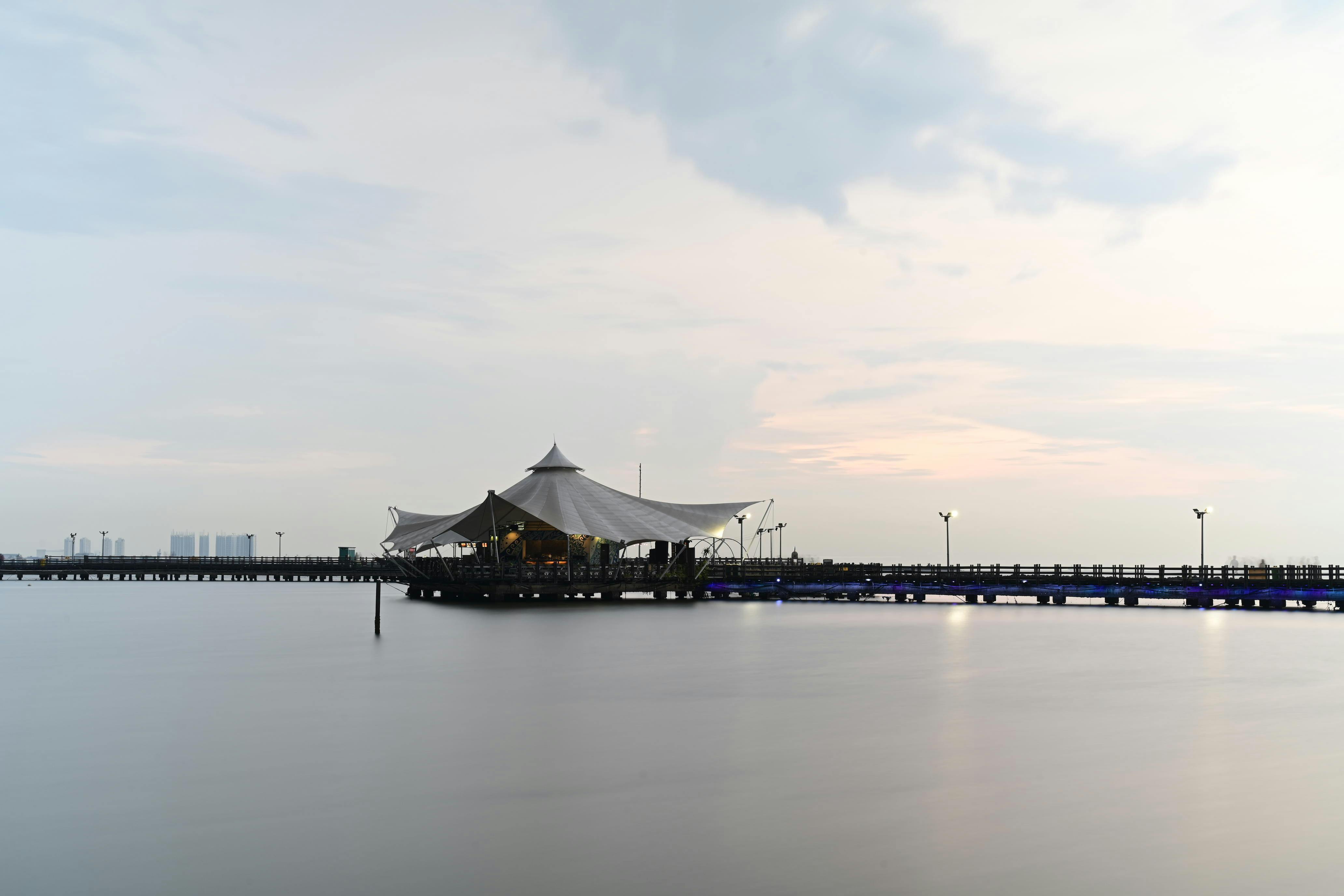 무료 자카르타 해안가의 부두와 정자가 잔잔한 물결과 어우러져 평화로운 황혼녘 풍경을 자아냅니다. 스톡 사진