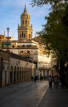 Charming city street with a bell tower, capturing historic European architecture at sunset.