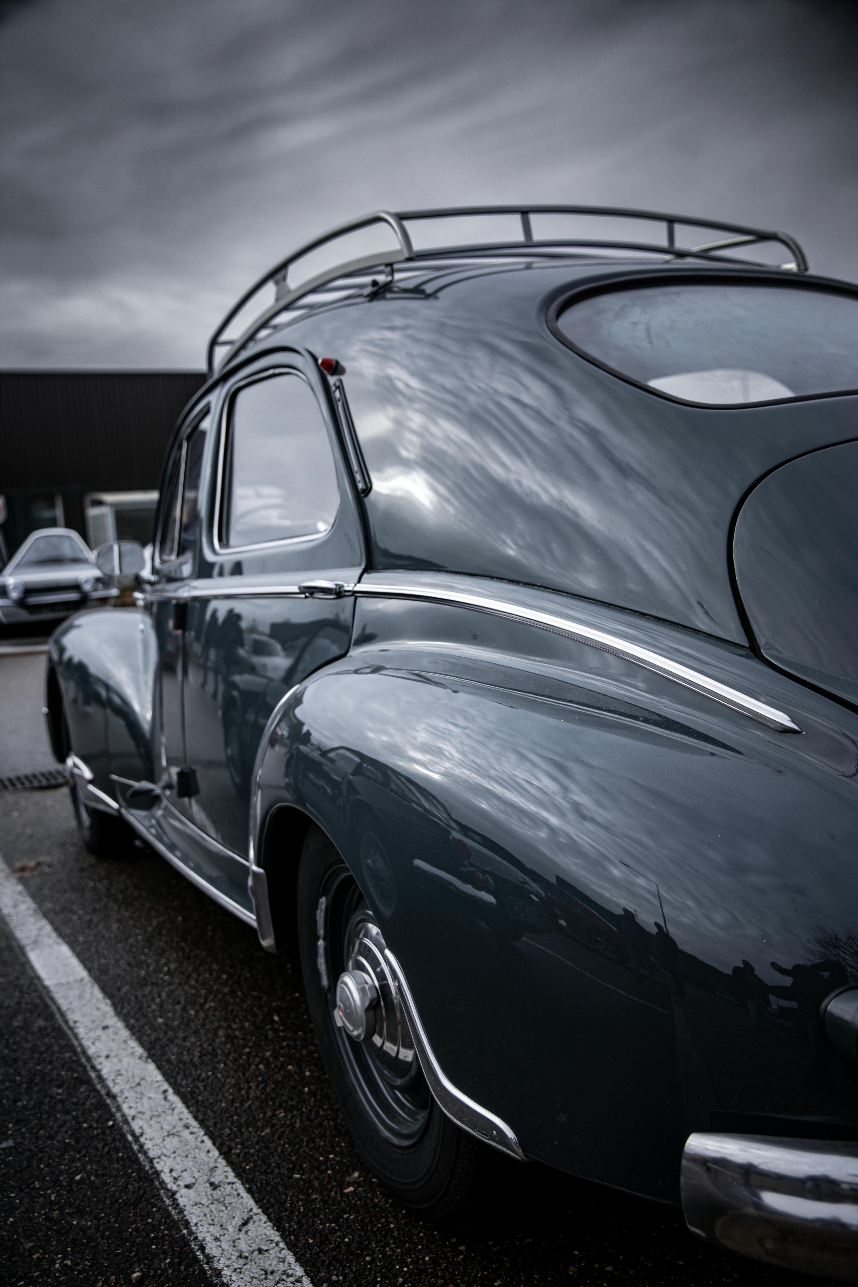 Gratuit Élégante voiture noire vintage garée à l'extérieur sous un ciel dramatiquement couvert. Photos