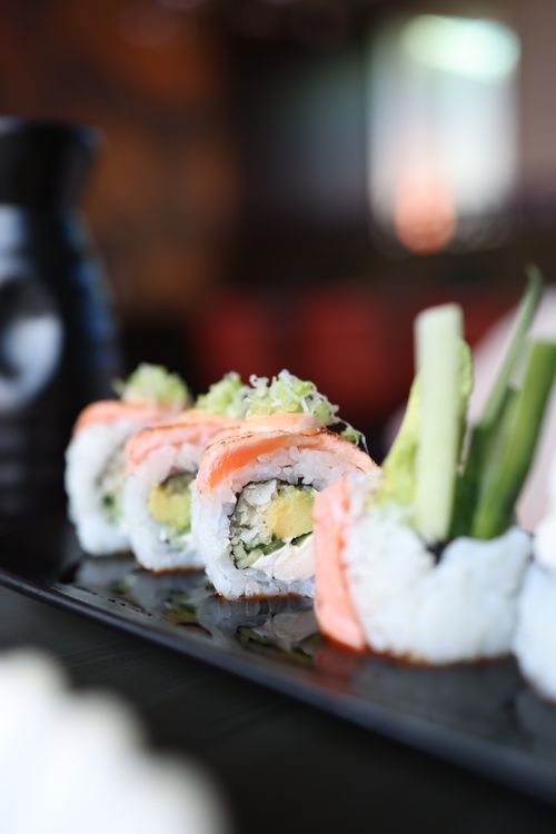 Free Delicious sushi rolls with salmon, avocado, and cucumber, elegantly presented on a black plate. Stock Photo