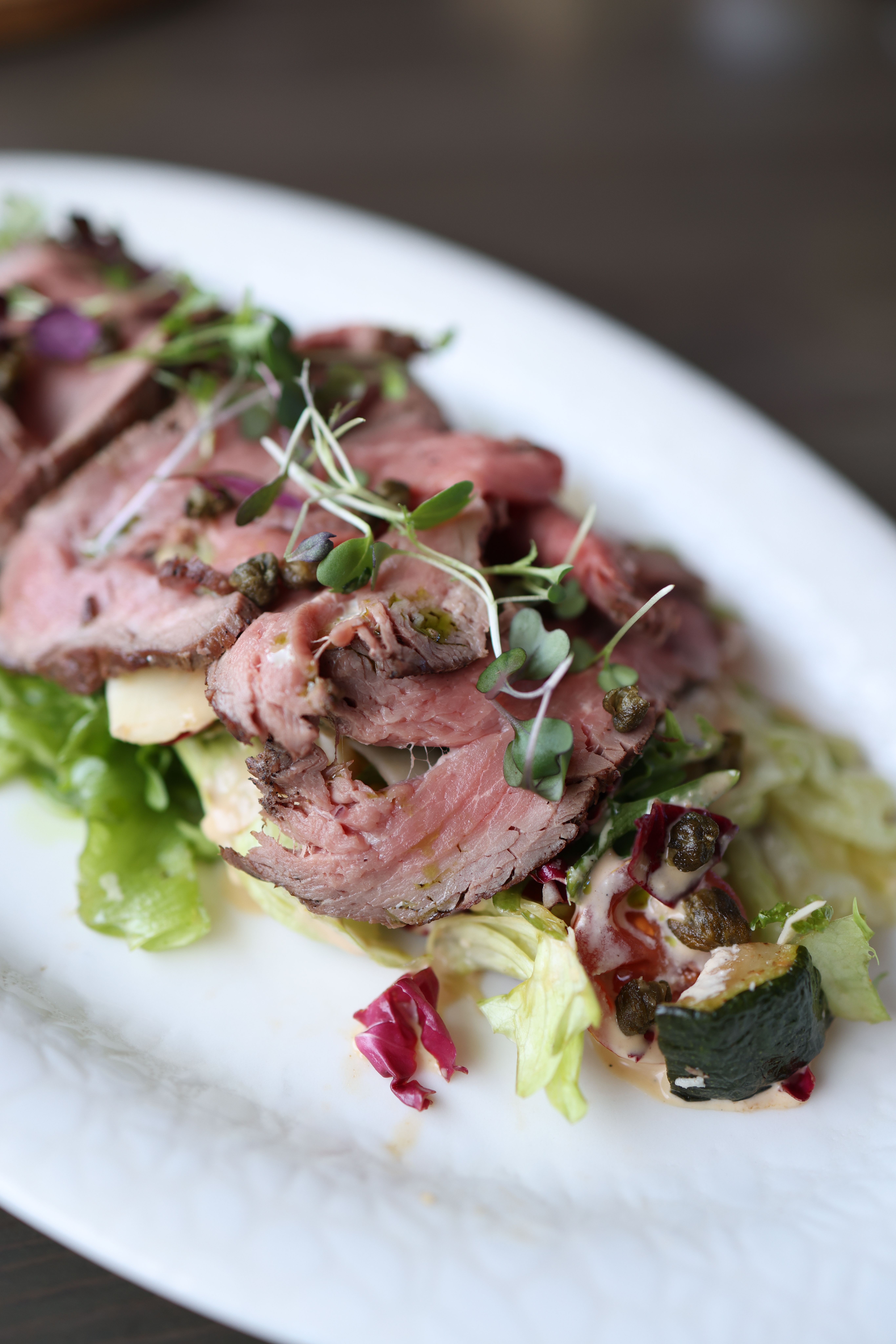 Juicy slices of roast beef served with fresh salad greens, perfect for a gourmet meal.